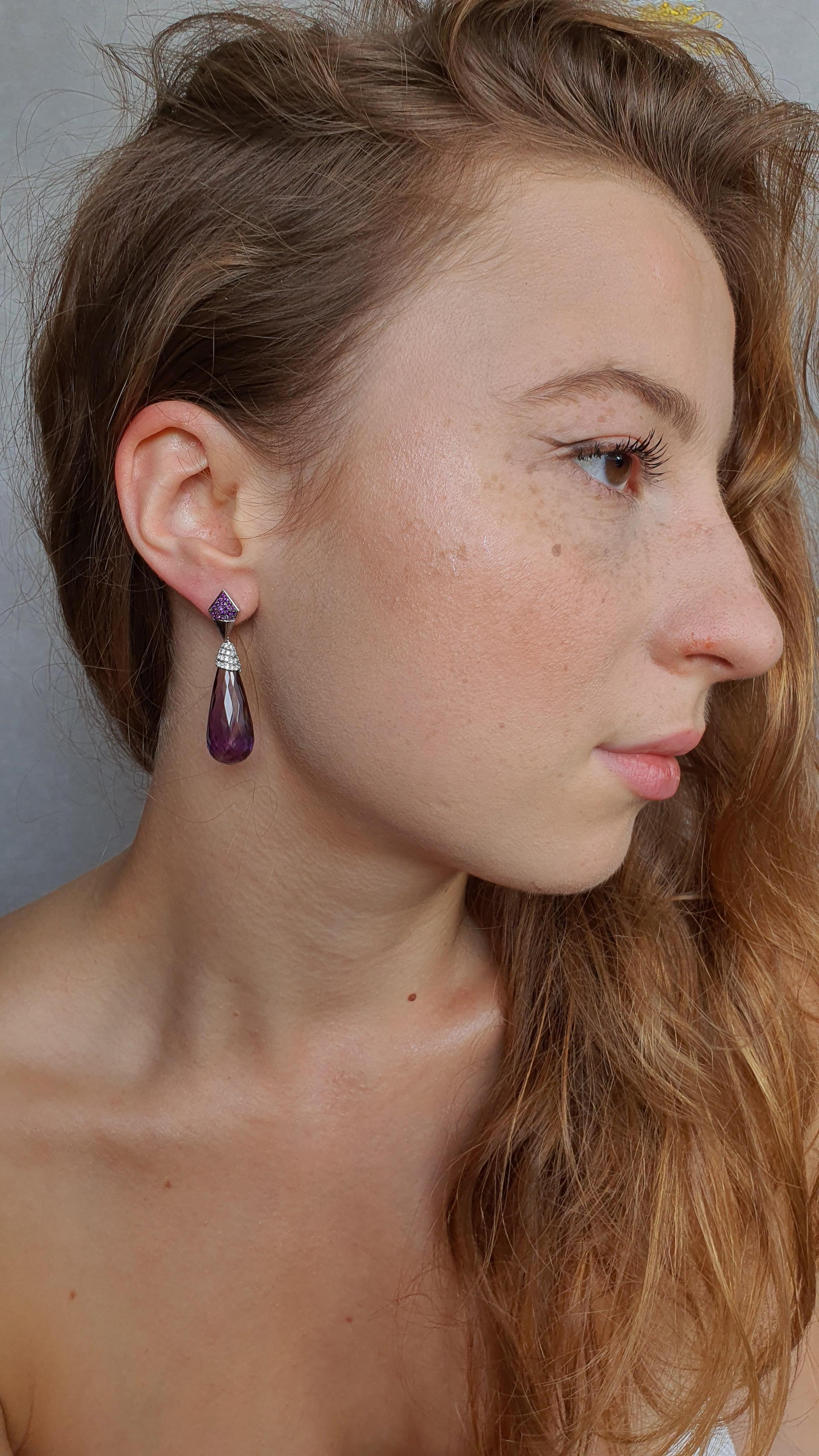 These beautiful earrings feature pampel shaped 42.79 Carat Amethysts and 96 round diamonds. Purple gemstones are often associated with royalty and power  which makes these earrings look more noble. The 18 Karat White Gold here is a perfect base for