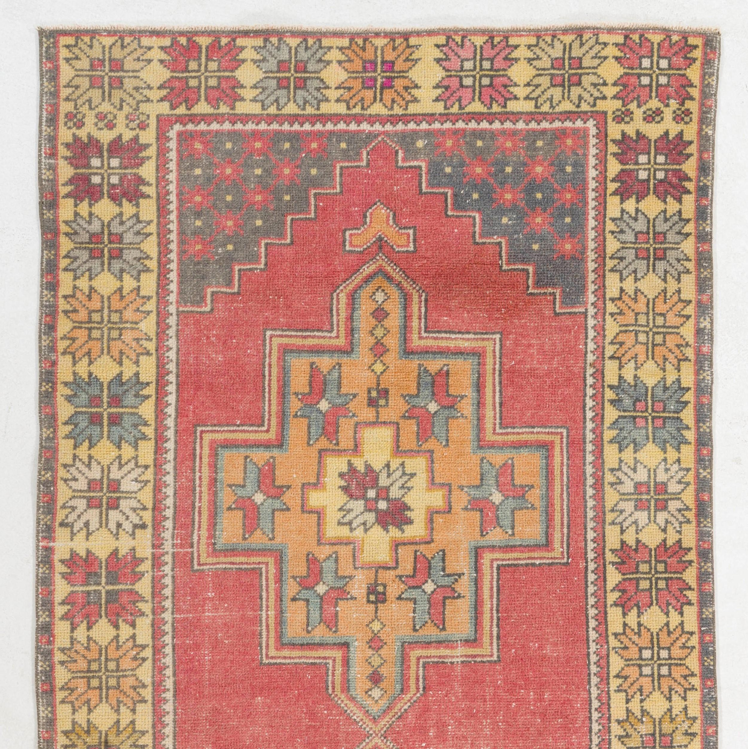 This vintage Central Anatolian rug has two linked geometric medallions at its center in soft, faded orange that are decorated with colorful abstract stars against a rich, dark coral pink. The corner-pieces are in dark indigo and feature a dense
