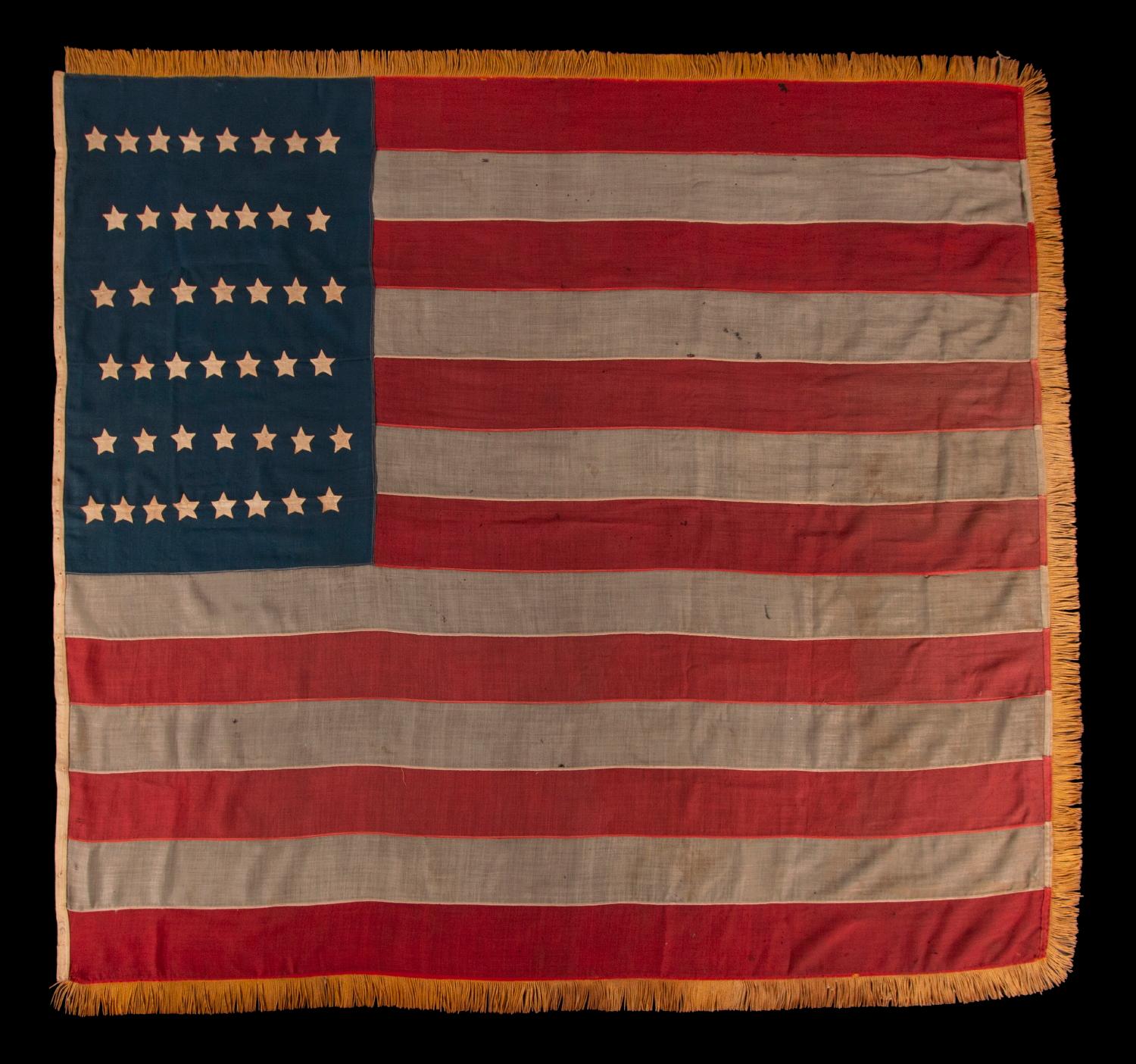 44 STARS ON AN ANTIQUE AMERICAN FLAG WITH AN EXAGGERATEDLY TALL AND NARROW CANTON, ON A U.S. ARMY REGULATION BATTLE FLAG MADE DURING THE LATE INDIAN WARS PERIOD, REFLECTS THE RECENT ADDITION OF WYOMING TO THE UNION, 1890-1896:

This rare and
