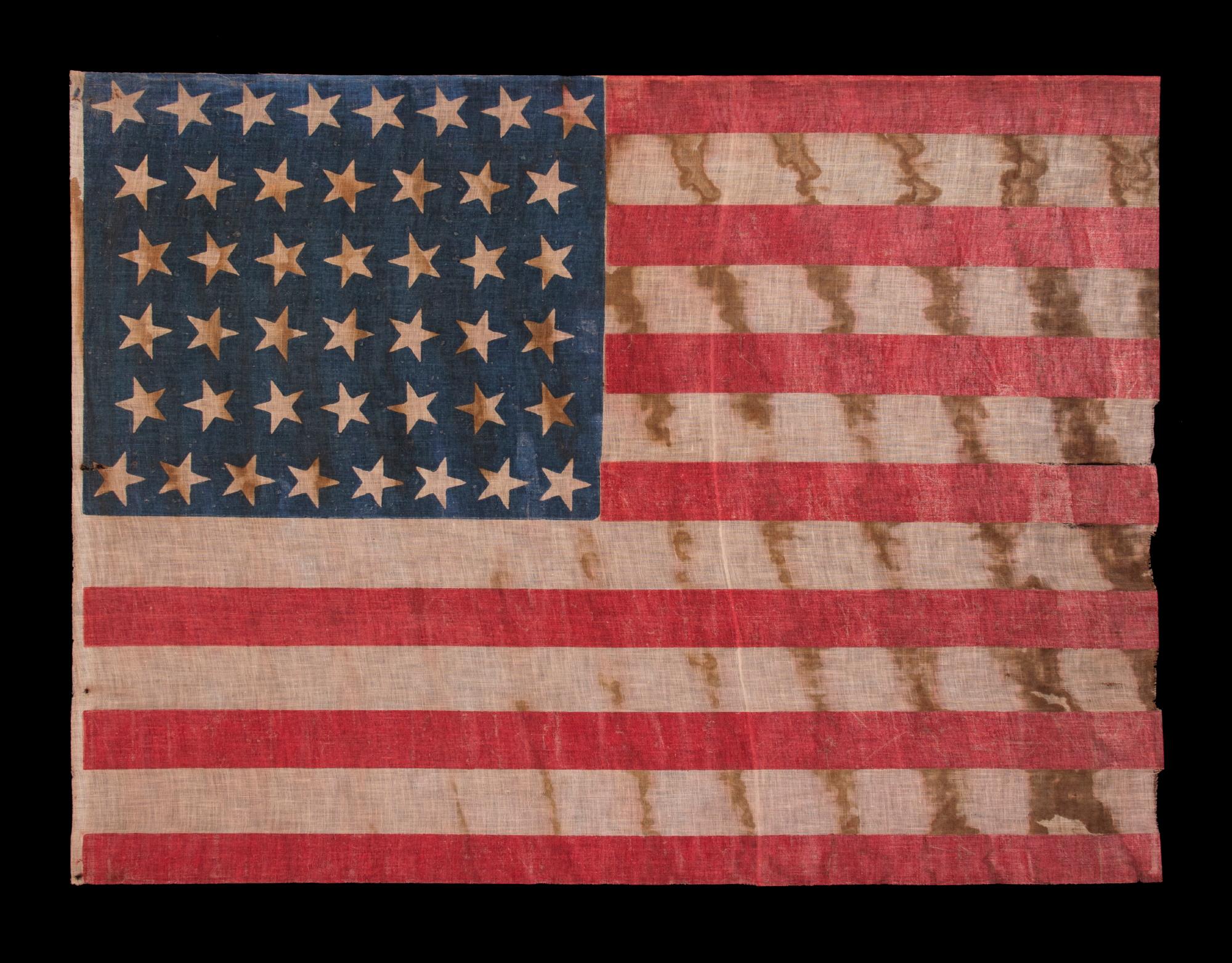44 STAR ANTIQUE AMERICAN FLAG WITH AN HOURGLASS FORMATION OF STARS IN CANTED ROWS, AND AN EXTREMELY INTERESTING PRESENTATION FROM REPEATING SWATHS OF HEAVY OXIDATION, WYOMING STATEHOOD, 1890-1896

Wyoming was admitted as the 44th state on July