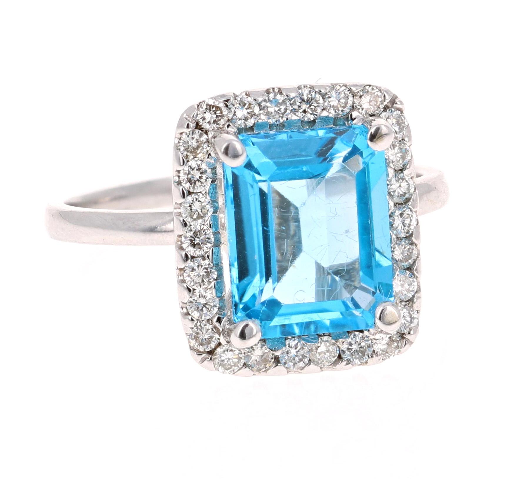 This stunning statement ring has a large Emerald Cut Blue Topaz that weighs 4.02 Carats. 
It is surrounded by a simple halo of 26 Round Cut Diamonds that weigh 0.38 Carats. 

It is crafted in 14 Karat White Gold and weighs approximately 4.6 grams.