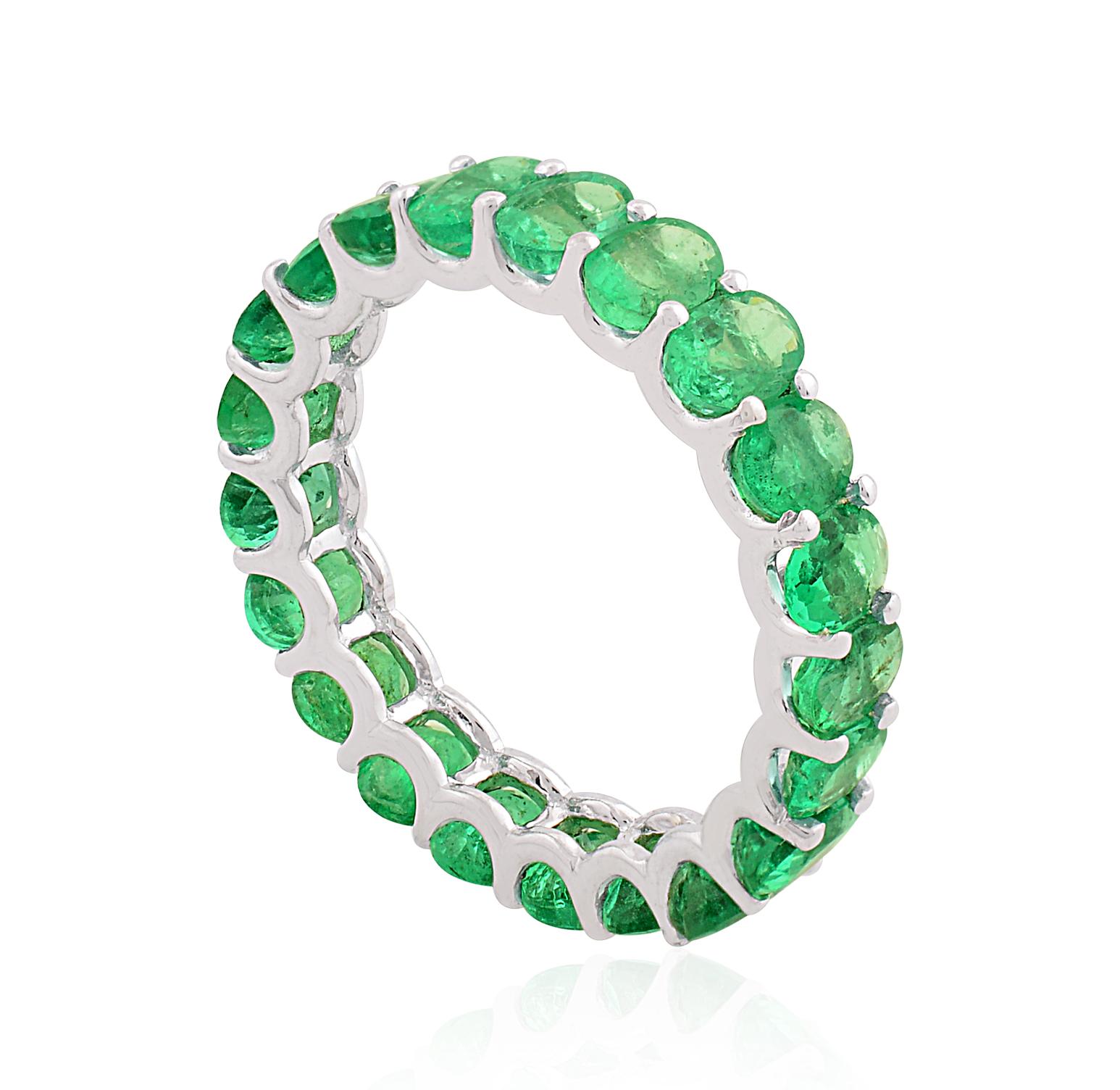 The emerald is delicately nestled within a band of gleaming 18 karat white gold, expertly shaped and polished to perfection. The purity and brilliance of the white gold complement the vivid green color of the emerald, creating a harmonious and