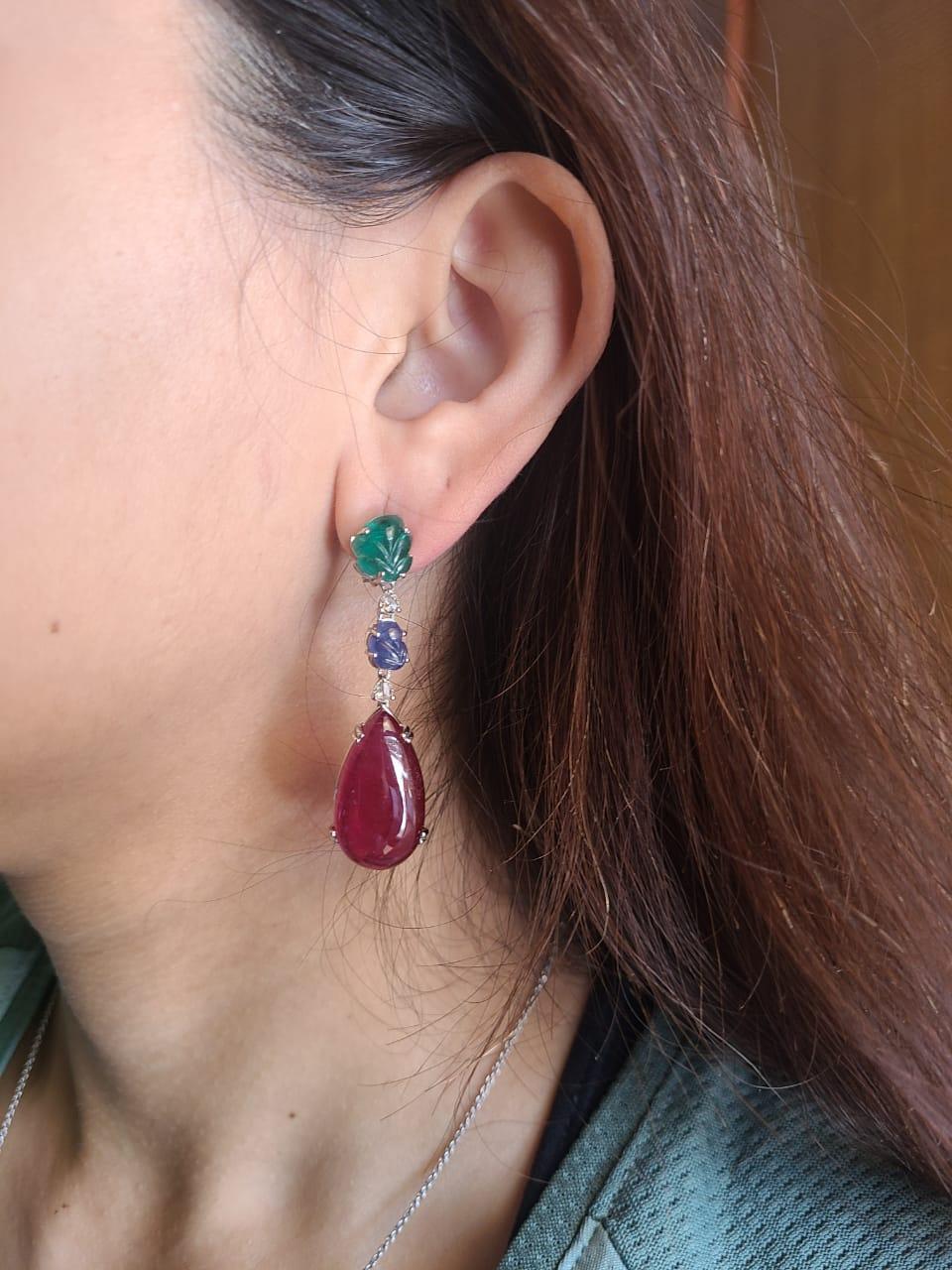 A very gorgeous and one of a kind, Rubellite, Emerald & Blue Sapphire Chandelier / Drop Earrings set in 18K Gold & Diamonds. The weight of the Rubellite pair is 44.04 carats. The weight of the carved Emerald is 4.43 carats. The Emeralds are of