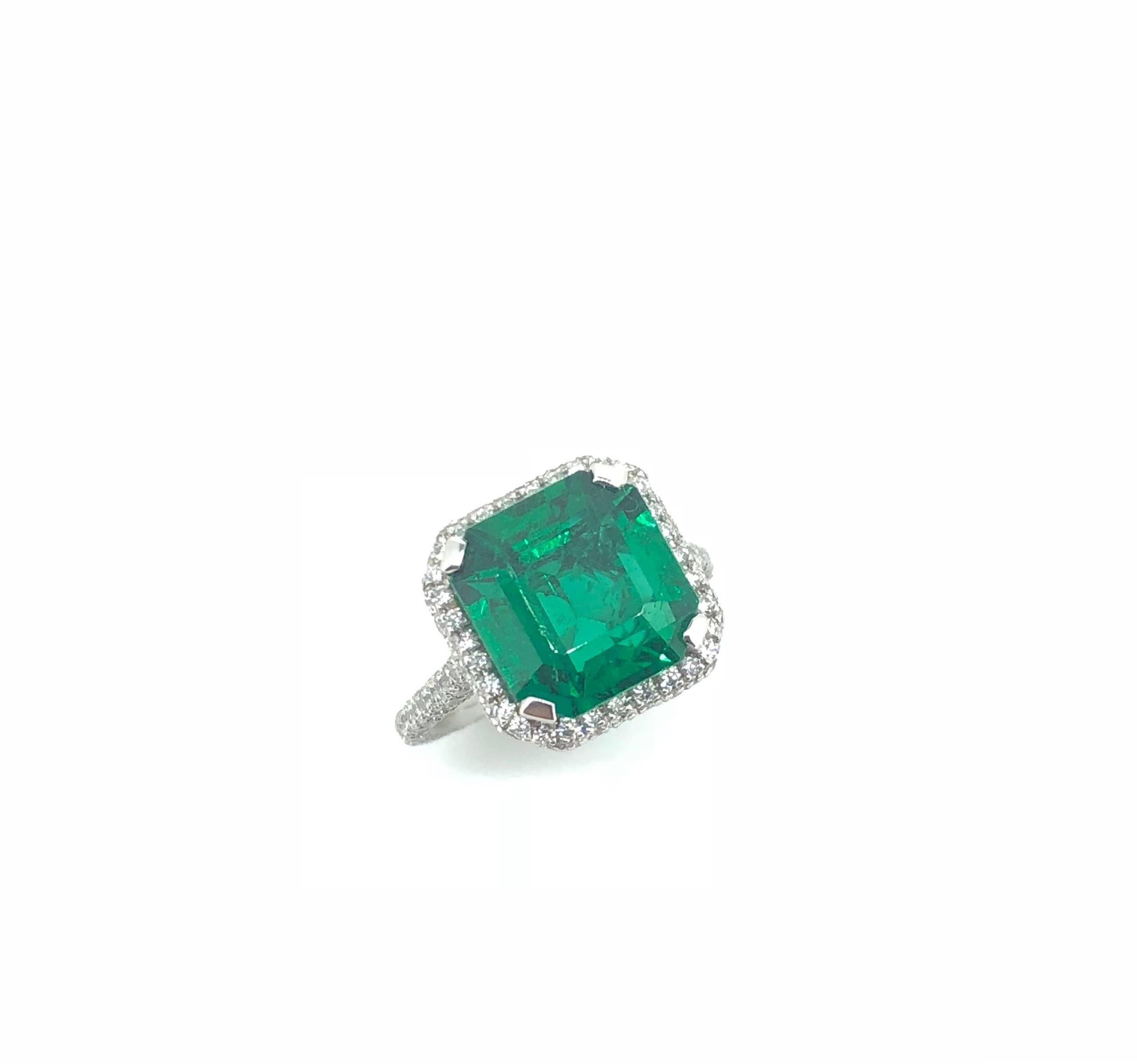 Emerald Cut  4.41 Carat mounted in Platinum Diamond Cluster Ring. 

The emerald exhibits vivid green colour with vibrant lustre mounted in modern diamond cluster ring. The setting and band fully encrusted with round brilliant cut diamonds in