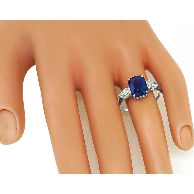 This is a gorgeous platinum engagement ring. The ring is centered with a lovely cushion cut sapphire that weighs approximately 4.41ct. The sapphire is accentuated by sparkling pear shape diamonds that weigh approximately 1.05ct. The color of these