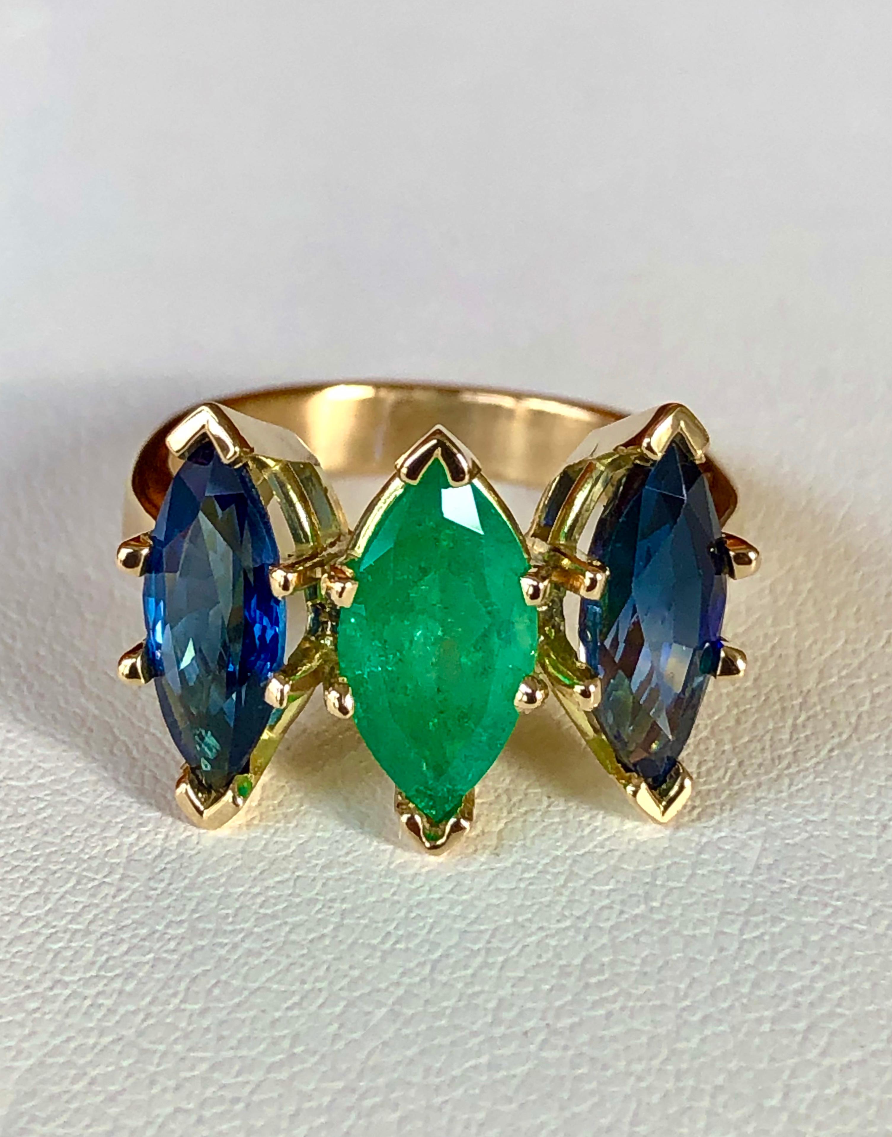 A SUPER RARE Find for this unique three stone ring features a center one marquise cut bright green natural Colombian emerald 1.38 carat , surrounded by two natural Ceylon sapphires marquise cut totaling 3.06 carat. The stones are carefully matched
