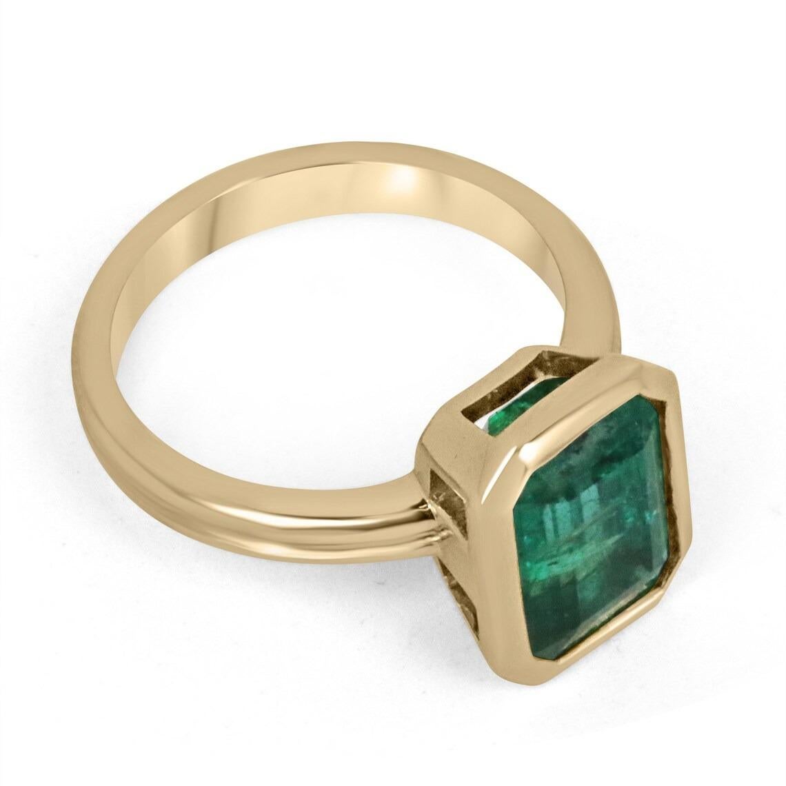 Displayed is a stunning emerald solitaire engagement or right-hand ring in 14K yellow gold. This gorgeous solitaire ring carries an estimated 4.45-carat emerald in a bezel setting. Fully faceted, this gemstone showcases excellent shine and