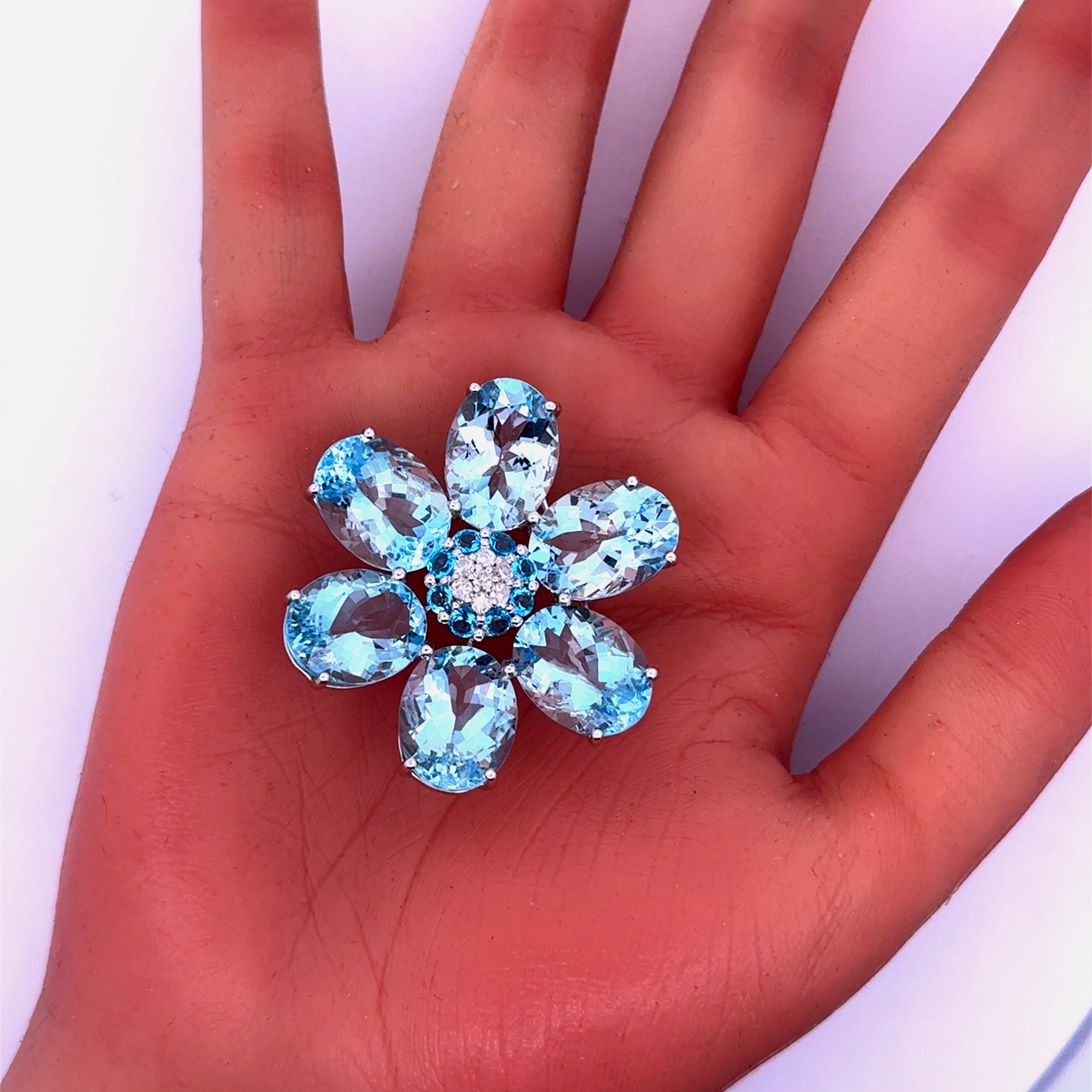 Un llamativo broche con un diseño floral, elaborado con 44,65 quilates de piedras de aguamarina talla oval, cada pétalo muestra un cautivador tono azul. El centro está adornado con 0,30 quilates de diamantes blancos talla redonda, que añaden un