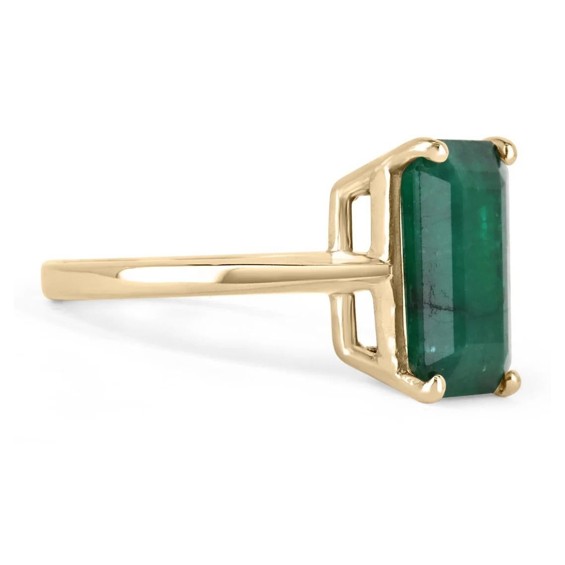 Displayed is a classic Brazilian emerald solitaire emerald-cut engagement ring/right-hand ring in 14K yellow gold. This gorgeous solitaire ring carries a full 4.46-carat emerald in an offset four-prong setting. Fully faceted, this gemstone showcases