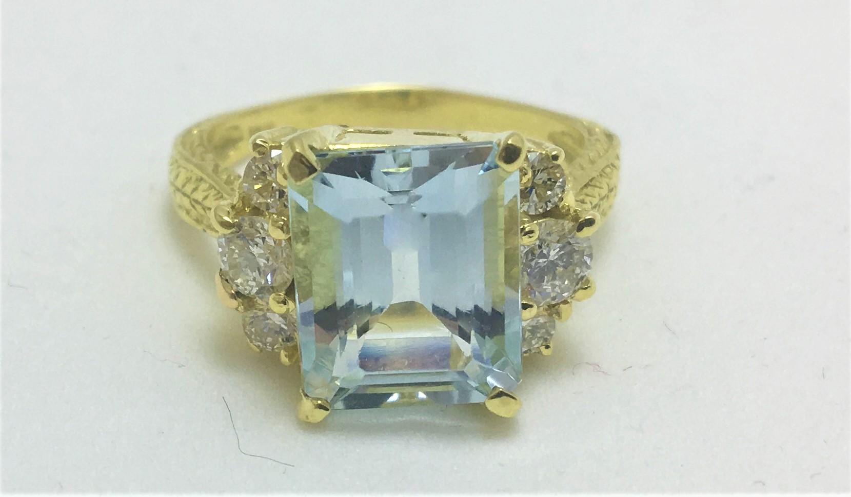 Emerald Cut Aquamarine Ring, approximately 4.49 carats, approximately 11 x 9 x 6.4mm
6 round diamonds (3 on each side of aquamarine), approximately .64 total diamond weight
18K yellow gold mounting with 