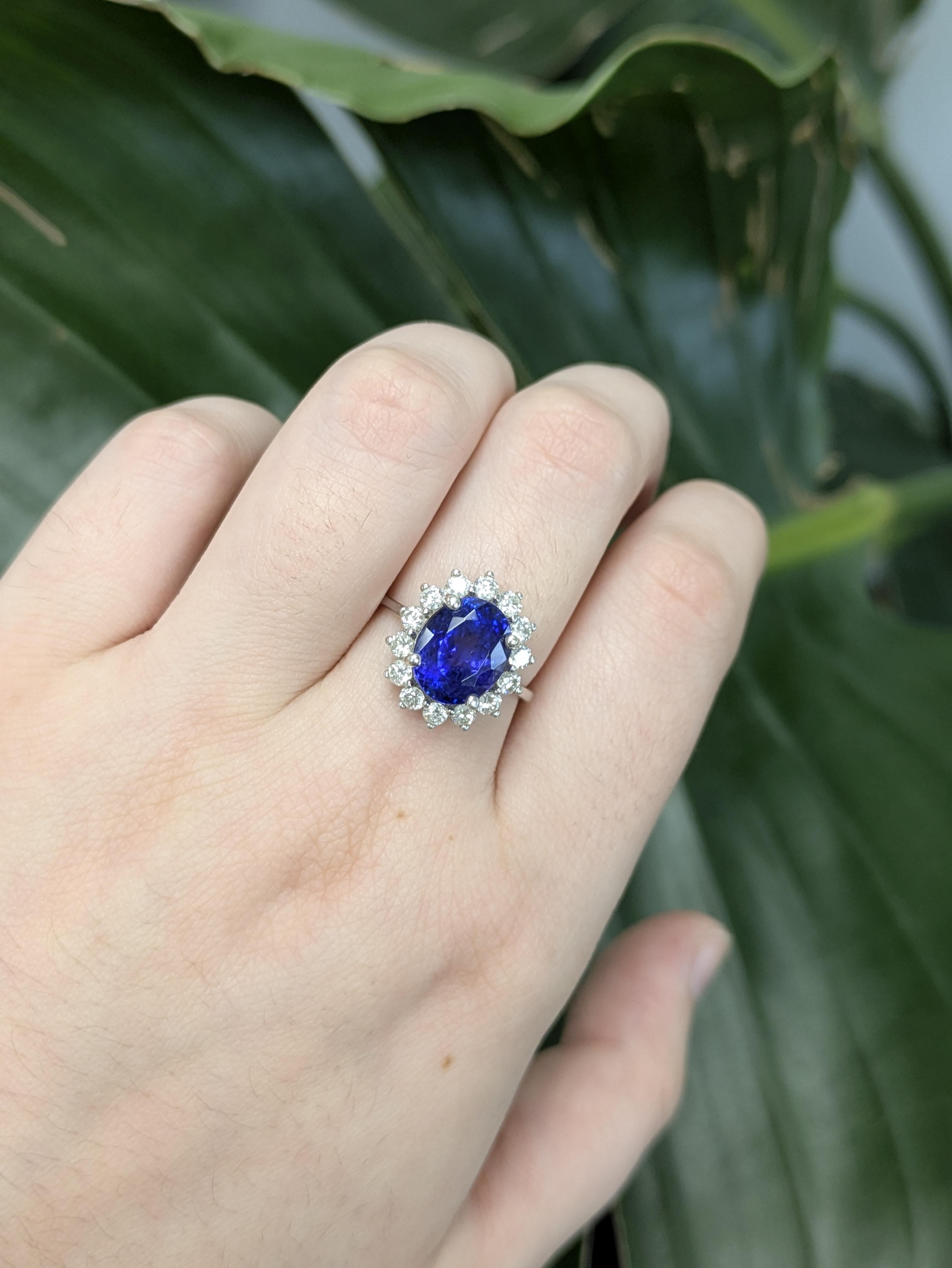 Questo elegante anello di tanzanite presenta una pietra centrale di forma ovale da 4,39 carati (10x8 mm) con straordinarie sfumature blu-viola. La gemma è splendidamente incastonata in una fascia d'oro 14k (3,08 g) e impreziosita da 14 diamanti