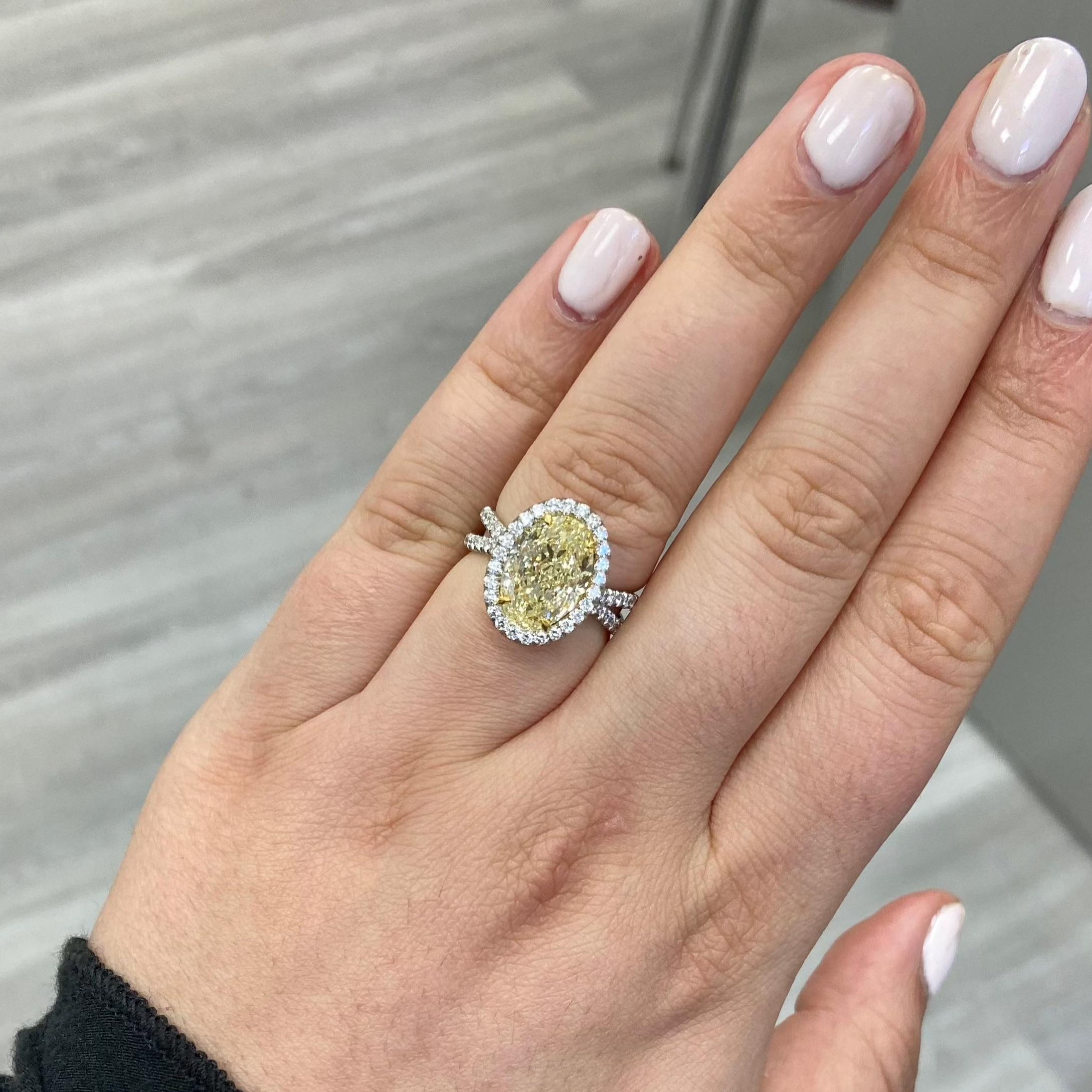 Beautiful 4 and a half carat light yellow  oval diamond set in a platinum and 18 karat yellow gold ring with a white diamond halo a twisted design shank. 
Color faces up like a fancy yellow diamond due to he 18 yellow gold.  
Stone is full of life,