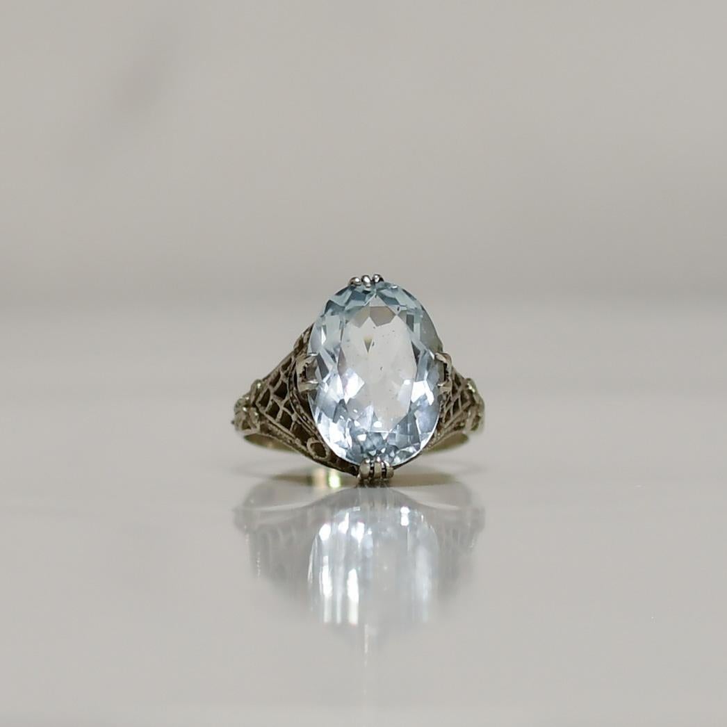 Elegance meets sophistication in this exquisite 14K White Gold ring, featuring a mesmerizing 4.5 carat aquamarine gemstone at its center. The delicate latticework and intricate ribbon detailing on the band add a touch of timeless charm to this