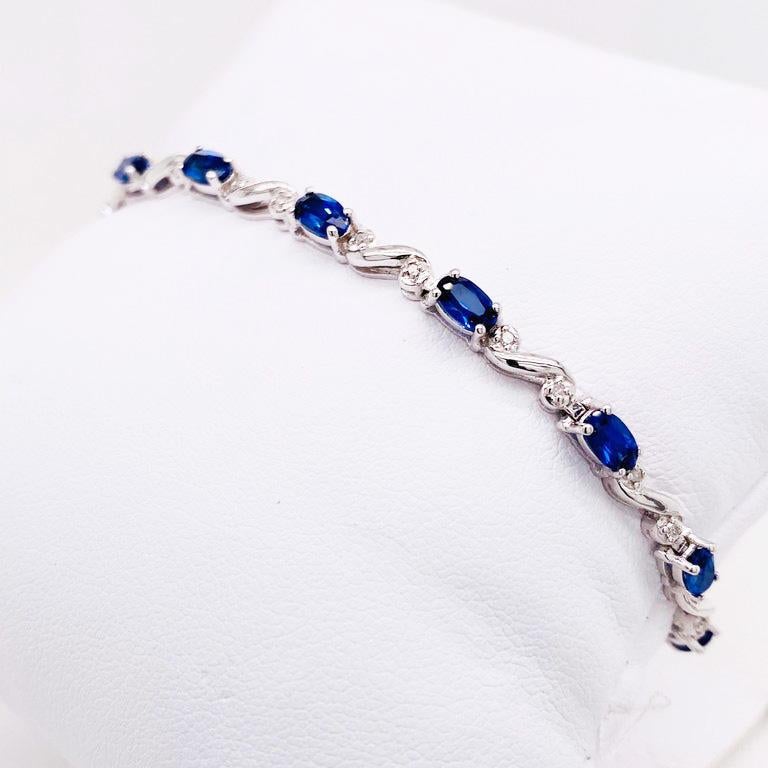 This is a traditional tennis bracelet with genuine blue sapphire gemstones and natural round brilliant diamonds. With oval blue sapphires set in between a whimsical sterling silver diamond design. Each sapphire has been hand picked to match the