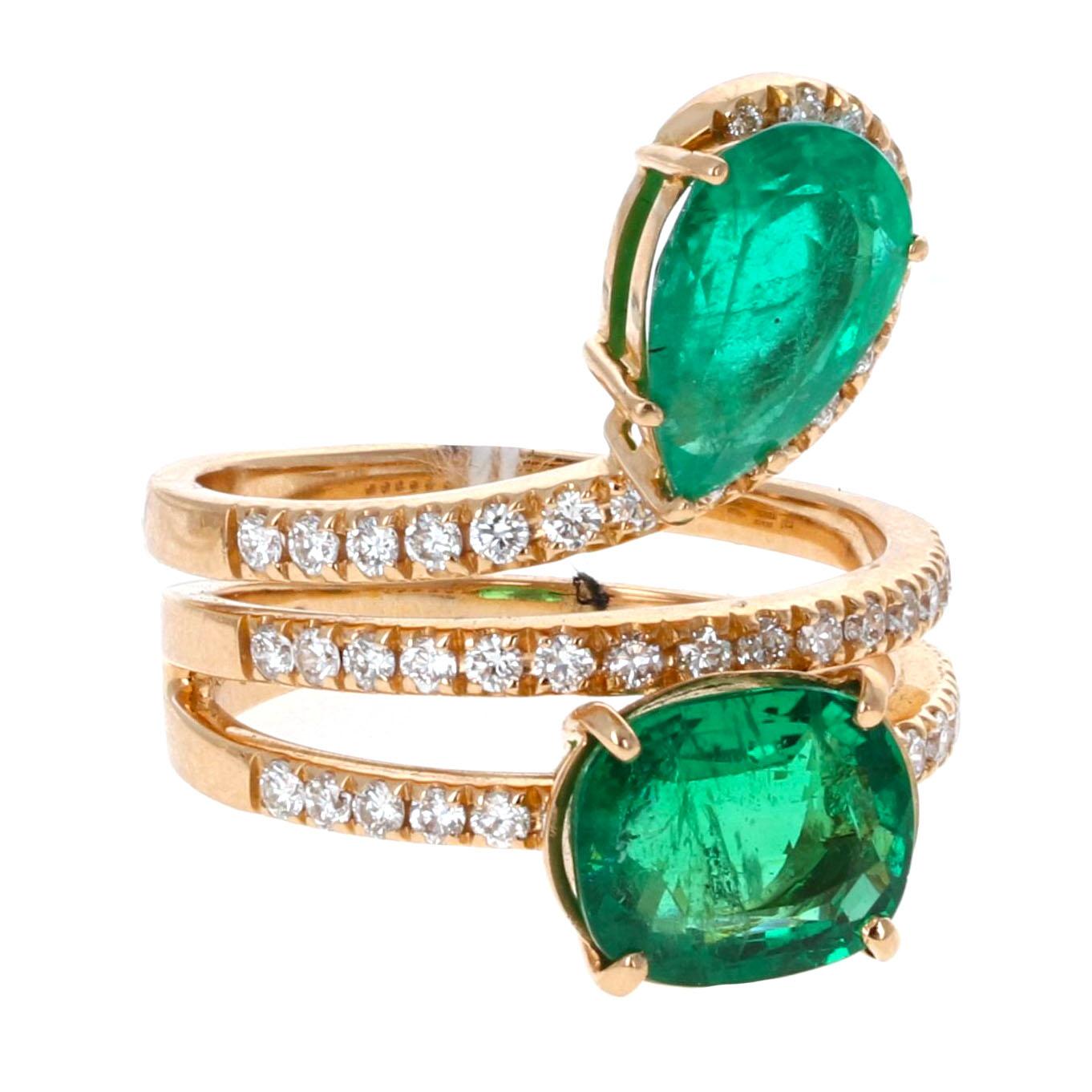 18 Karat rose gold emerald and diamond by-pass ring. This eye-catching piece features a striking three-tiered design with 2 vibrant emeralds weighing a total of 4.50 carats. The pear and oval-cut emeralds are accented by 0.30 carats of round