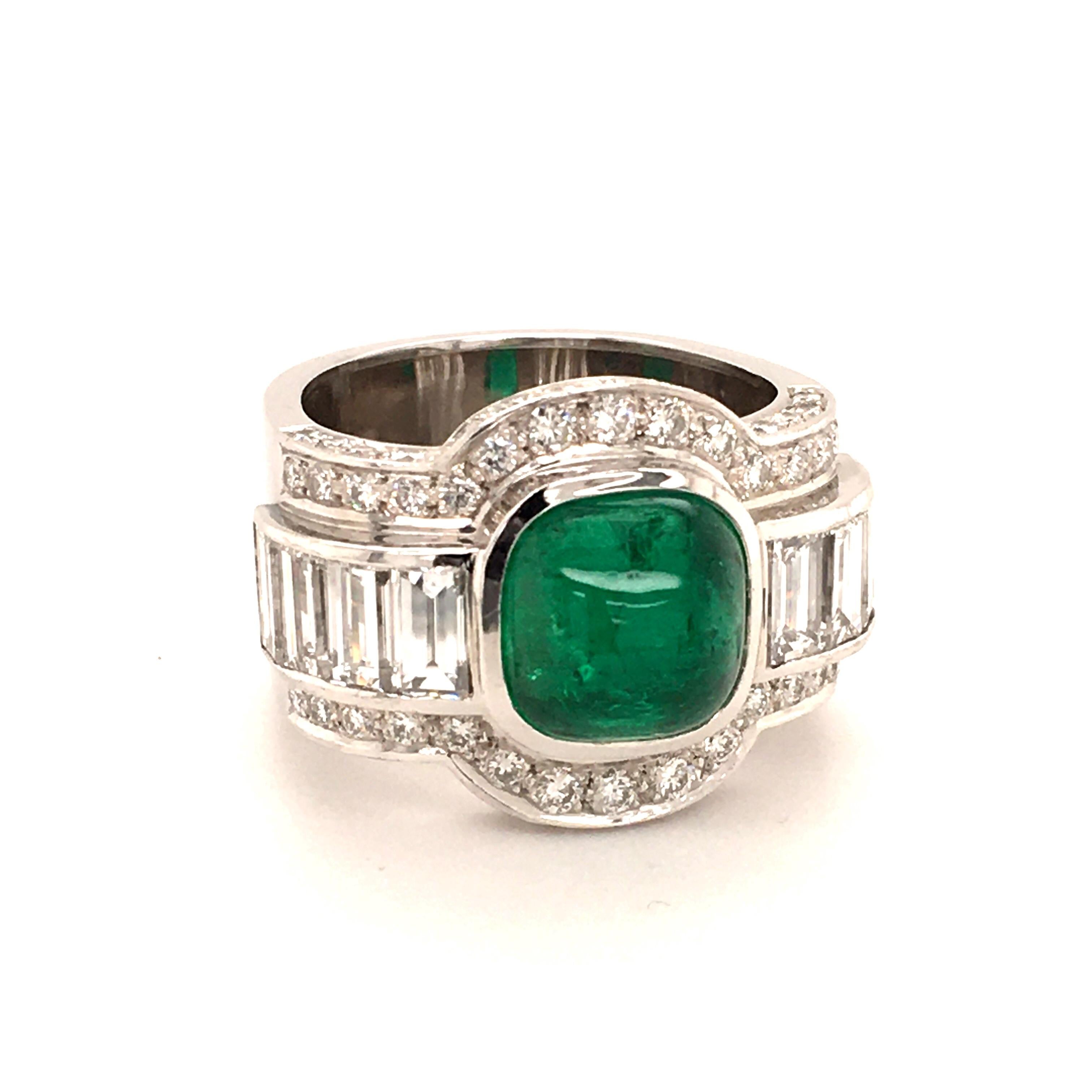 This bold ring in 18 karat white gold features a beautiful cushion shaped emerald cabochon of approximately 4.50 carats. The ring shoulders are set with 8 baguette shaped diamonds of G/H colour and vs clarity, total weight approximately 3.20 carats.