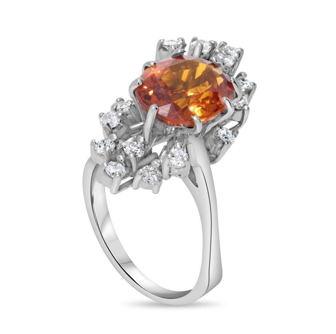 Dieser Saphir- und Diamantring zeigt einen atemberaubenden ovalen orangefarbenen Saphir von 4,20 Karat, umgeben von Diamanten von 0,50 Karat Gesamtgewicht. Die Fassung aus 18 Karat Weißgold bietet einen eleganten und modernen Hintergrund, der die