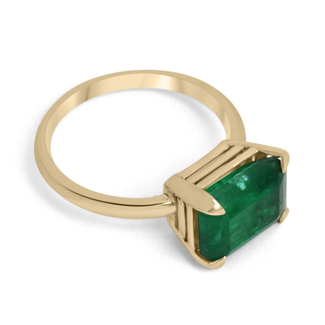 Displayed is a gorgeous emerald solitaire ring. This special piece features a remarkable, dark foresty green emerald cut emerald. The gemstone carries a hefty 4.50-carats of very good luster and clarity. Handset east to west in a custom four-prong