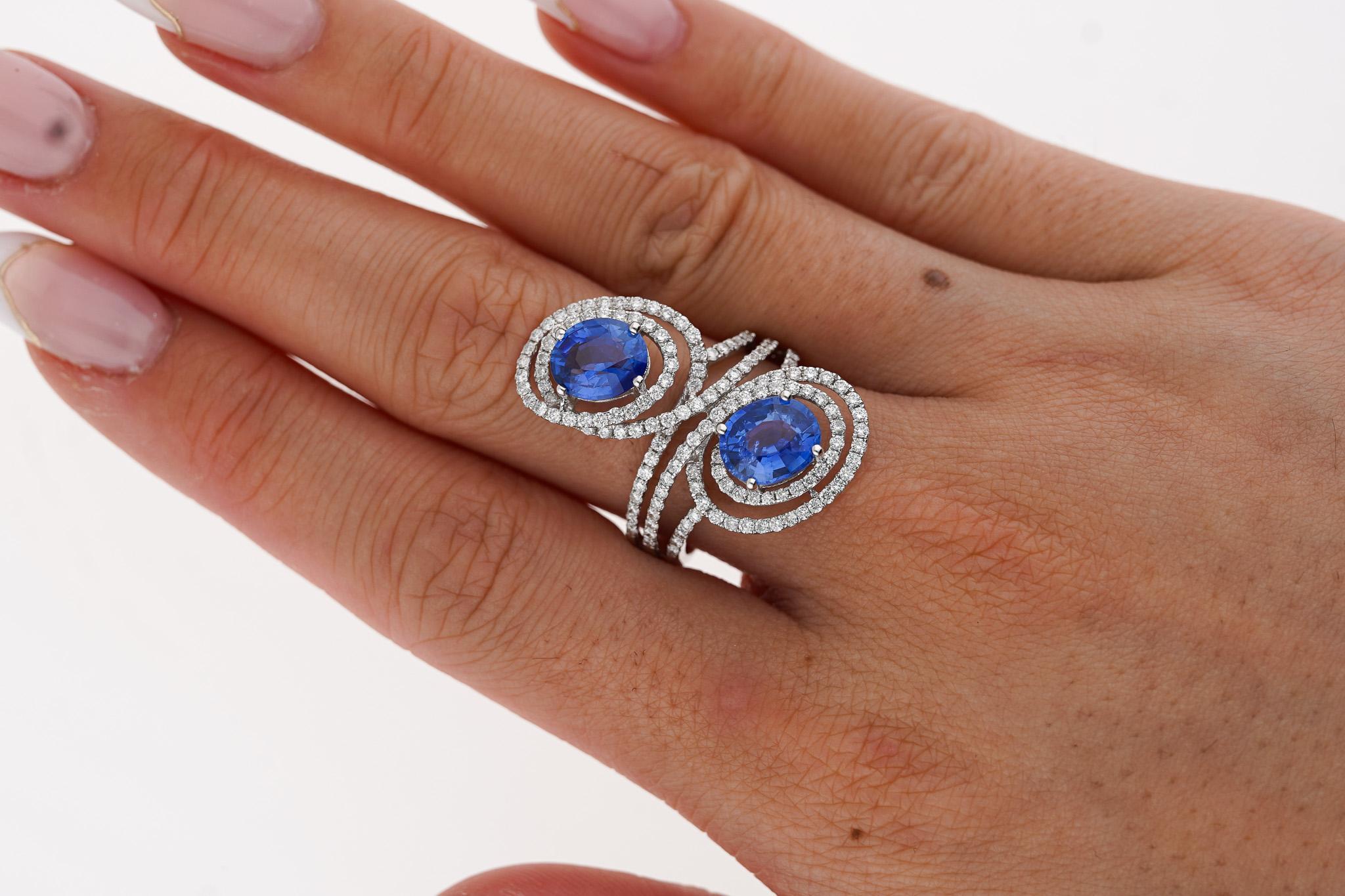 3.41 carat oval cut blue sapphire and diamond ring. Adorned with diamonds that total 1.10 carats and the ring goes horizontally on the finger create this east west setting. The diamonds are F-G color with VS2-SI1 clarity. The sapphires and diamonds