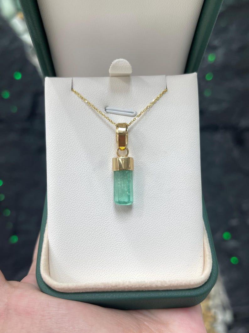 Nous vous présentons notre pendentif en émeraude brute naturelle, une pièce distinctive et unisexe mettant en valeur la beauté brute d'un cristal d'émeraude terminé de 4.51 carat provenant des paysages verdoyants de la Colombie. Le cristal brut et