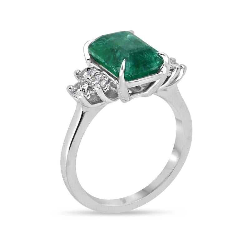 Introducing our breathtaking emerald and diamond seven-stone ring, showcasing a striking over four-carat emerald cut emerald set north to south in a secure four-prong setting. Its captivating dark green hue, semi-transparent clarity, and unique
