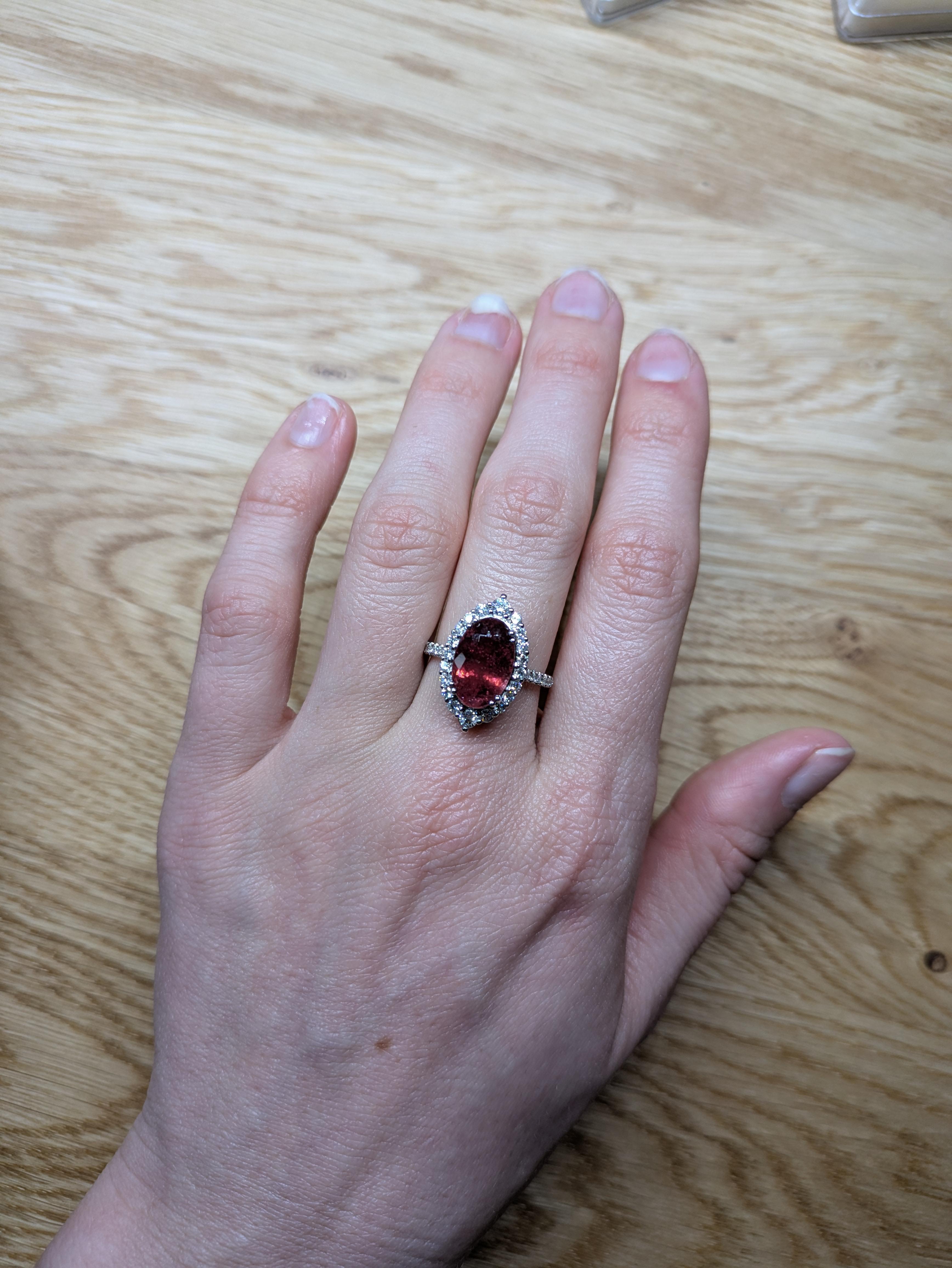 14K White Gold Rubellite Diamond Ring features a stunning 4.52-carat Rubellite gemstone, with an oval shape measuring 13.3x8.6mm. Known for its vibrant pink to red hues, the Rubellite is the centerpiece of this exquisite design. Surrounding the