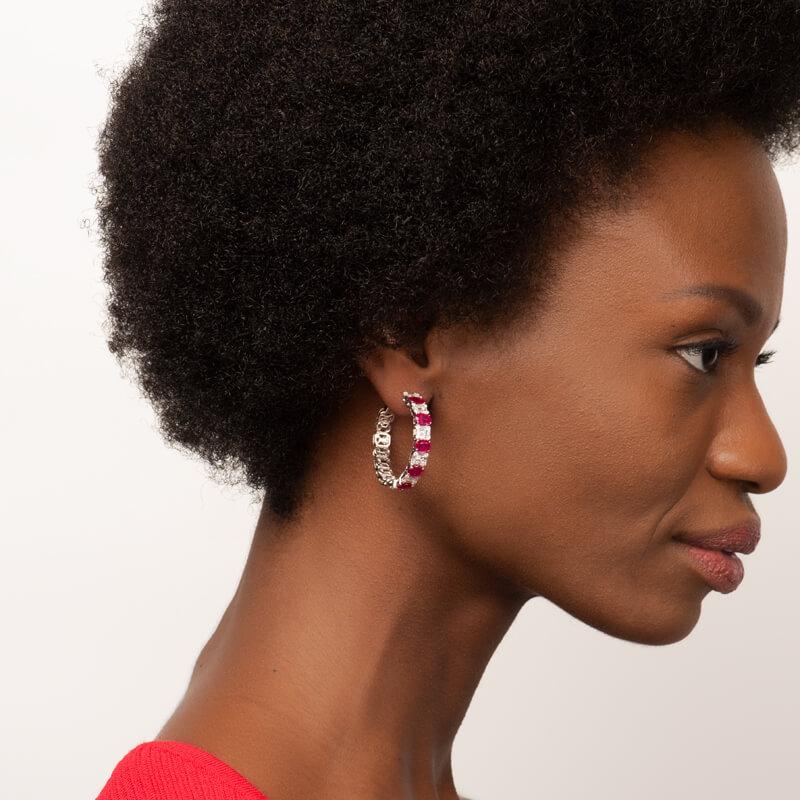 These hoop earrings feature 4.53 carat total weight in oval cut natural rubies alternating with 2.71 carat total weight in baguette and round diamonds set in 14 karat white gold.