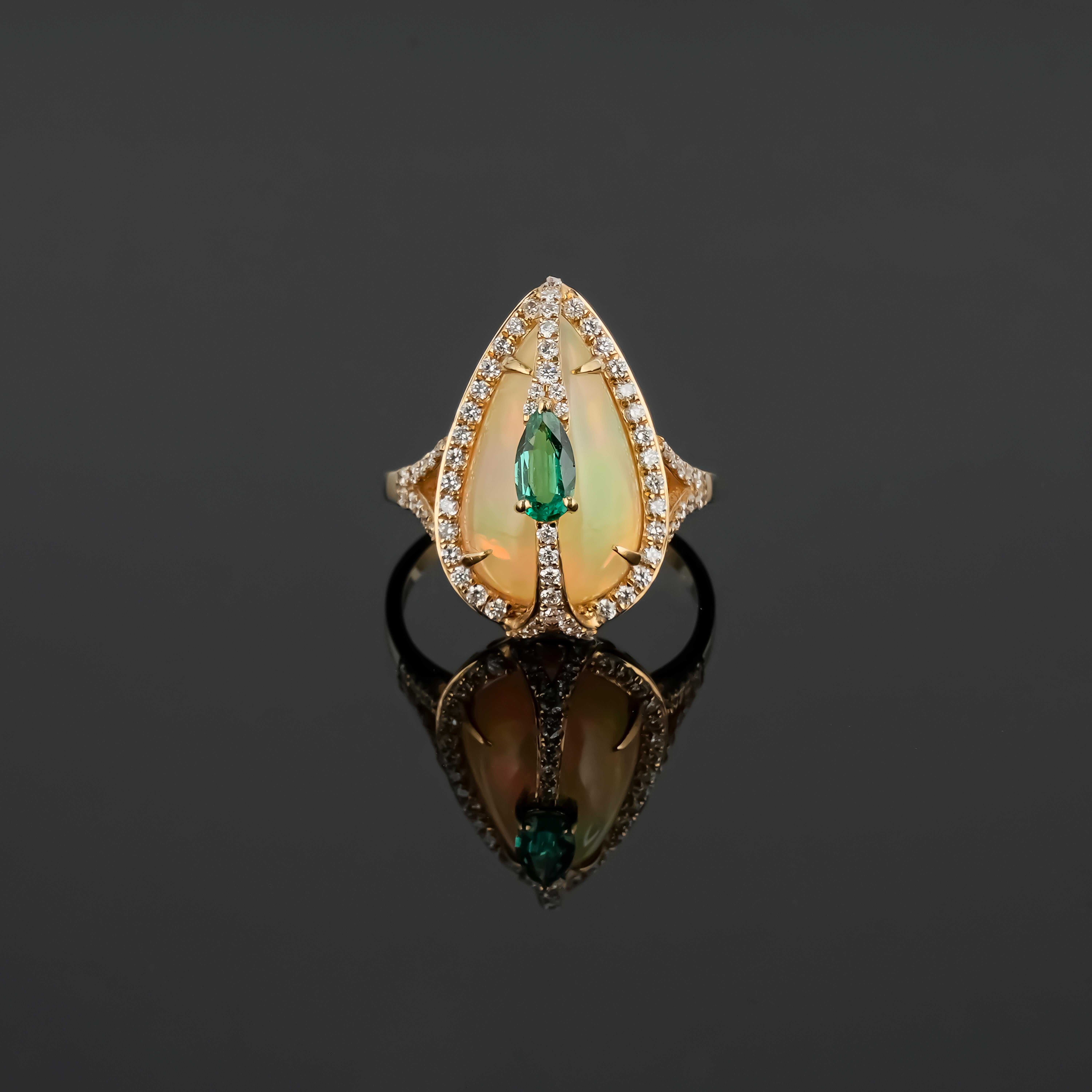 A beautiful, 4.56 carat pear cabochon shaped Opal cocktail ring, adorned with a 0.24 carat pear shape Emerald in the center, and 0.5 carat round Diamonds. The Opal has a beautiful hue of mixes colors, making the Emerald center piece a great