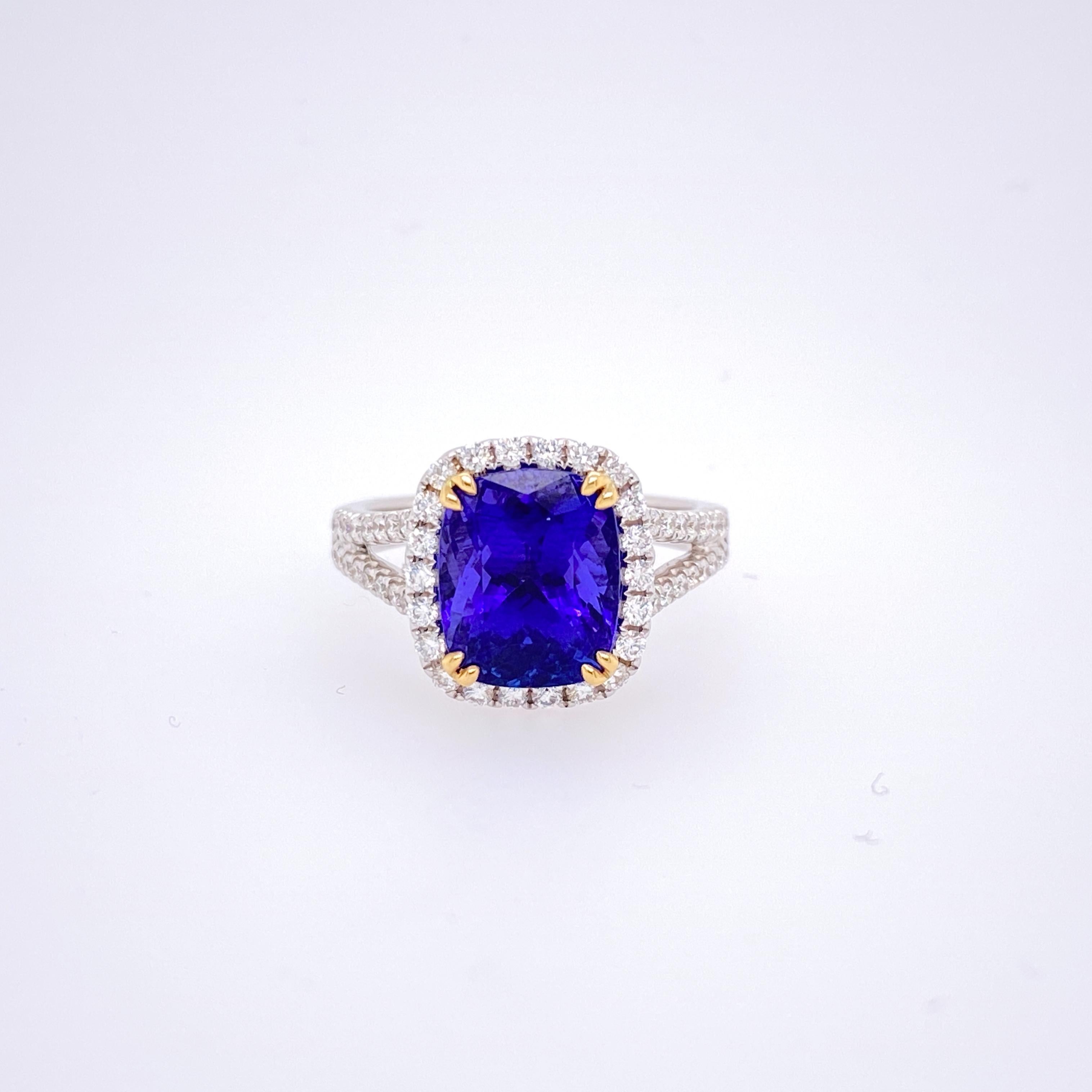 This beautiful cocktail ring features a stunning 4.57 Carat Cushion Tanzanite with a Diamond Halo, on a Double Diamond Shank. This Ring is set in 18k White Gold, with 18k Yellow Gold prongs on the center stone. Total Diamond Weight = 0.59 Carats.