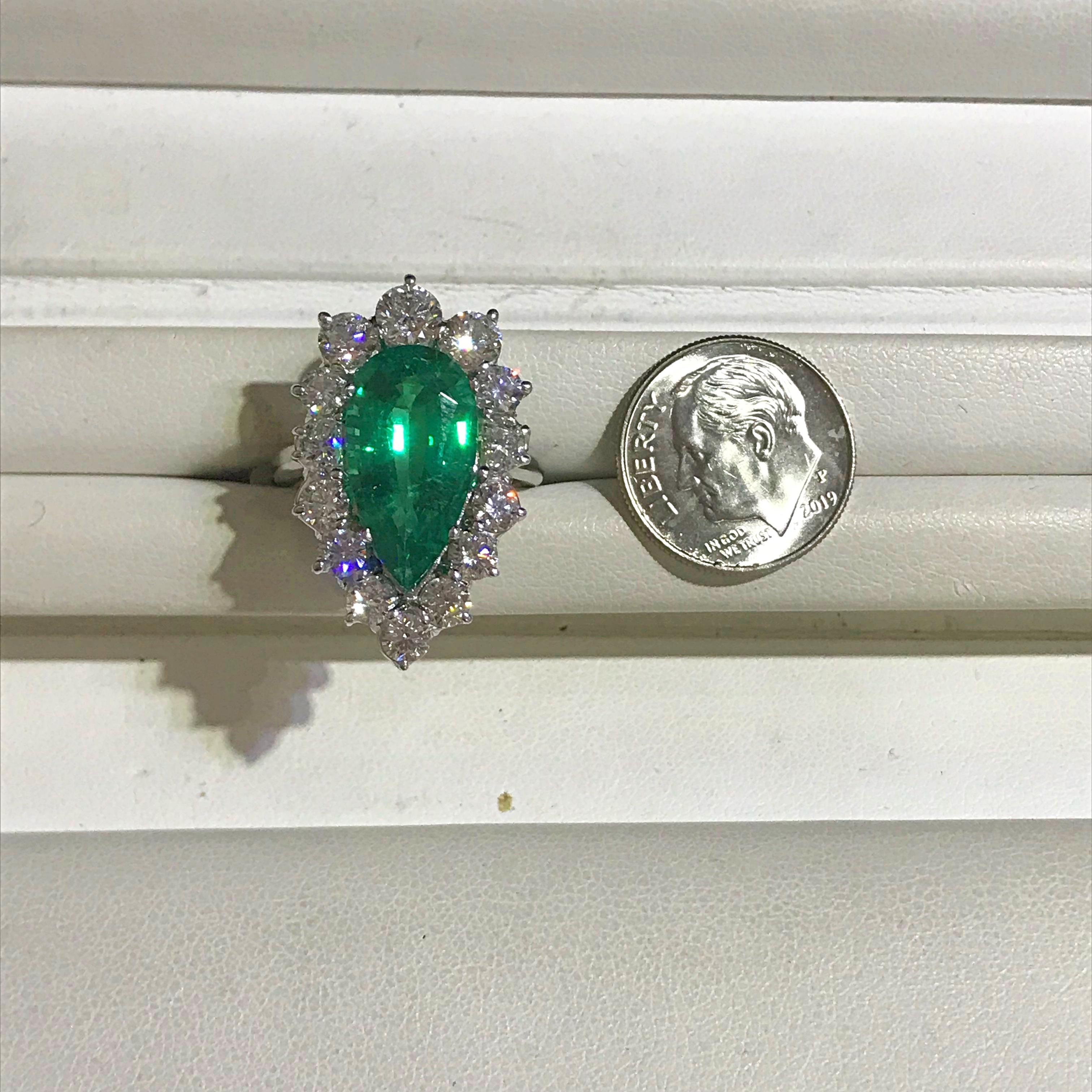 This vivid green Emerald is an elongated pear shape and fashionably surrounded by 2.48 carats total weight of diamonds. The ring is crafted from Platinum and is currently a size 6. The ring is sizeable. Please contact us with any questions or