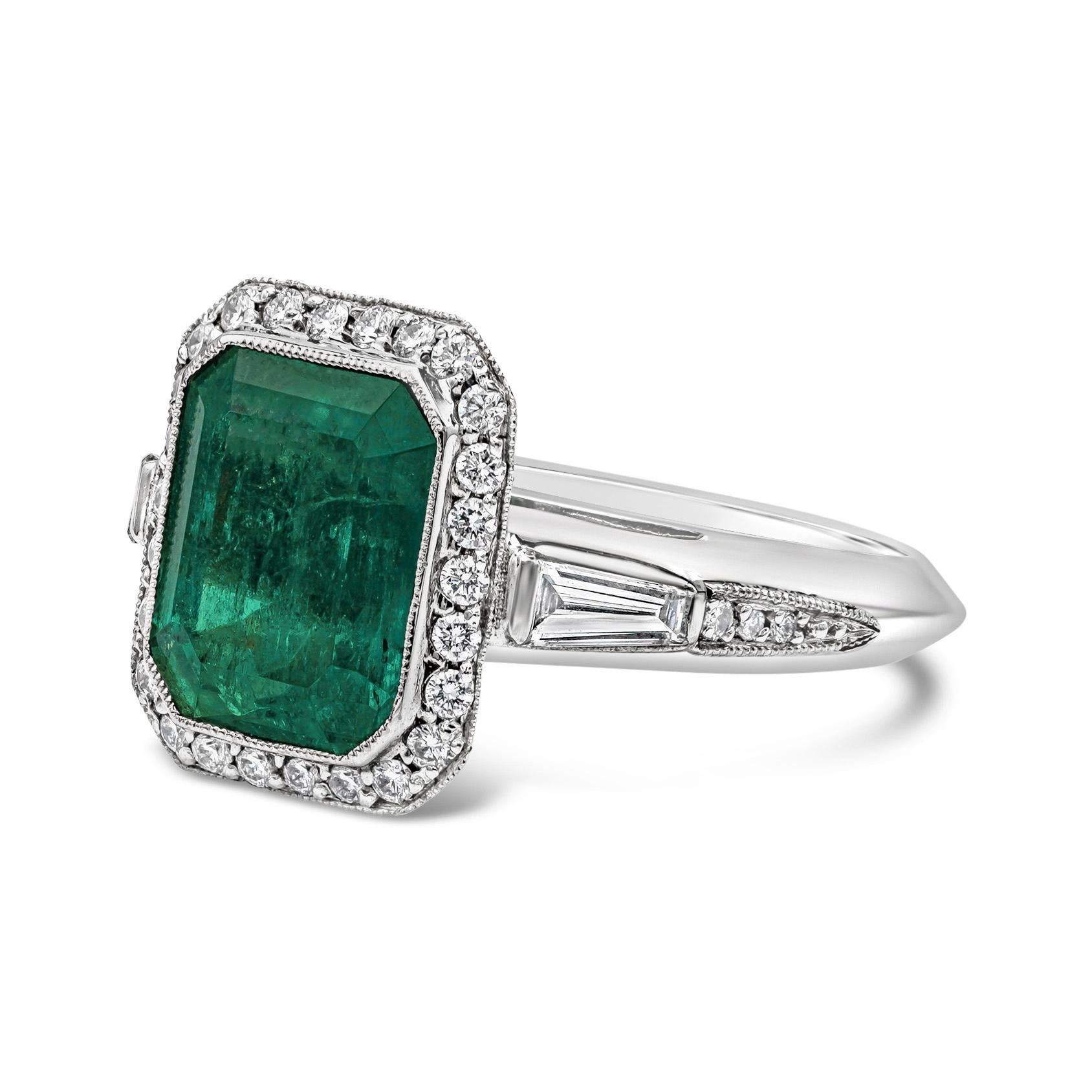 A stunning gemstone engagement ring style showcasing an emerald cut green emerald center stone weighing 4.58 carat total. Surrounded by brilliant round diamonds in a halo design and accented with more diamonds set on each side of the shank. Diamonds