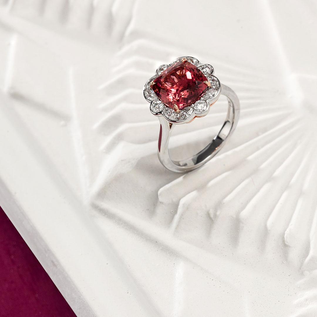 This beautiful Matthew Ely cocktail ring features a 4.58ct Cushion Cut Pink Tourmaline at its center,  surrounded by 0.90ct Round Brilliant Cut and Marquise Cut Diamonds. This ring is set with 18ct White and Rose Gold to highlight the spectacular
