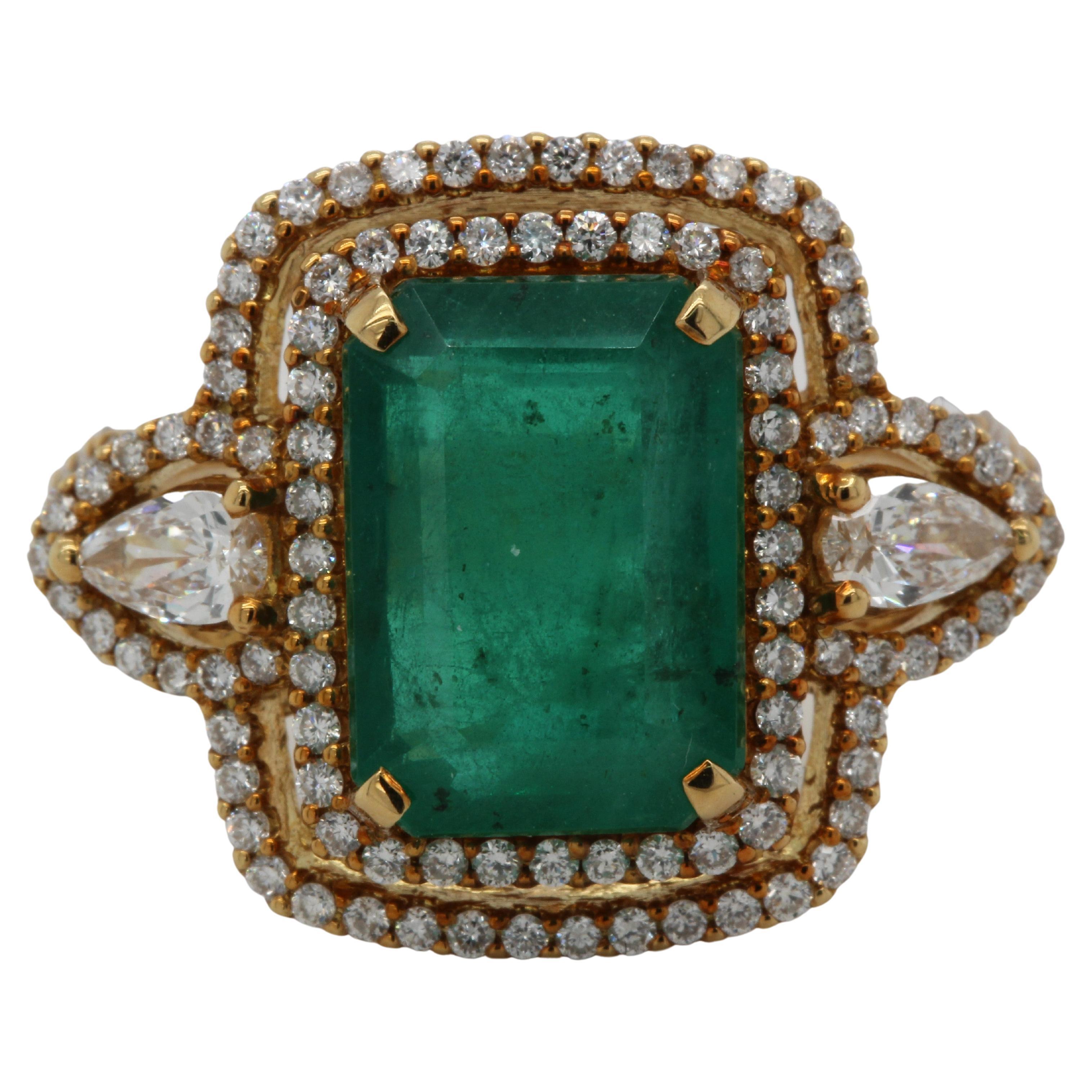 An elegant and luxurious addition to your collection, this 18K yellow gold emerald and diamond ring features a 4.59 carat emerald emerald cut in the center of the piece. Surrounded by 0.60 carat diamond round and 0.24 carat diamond pear, this ring