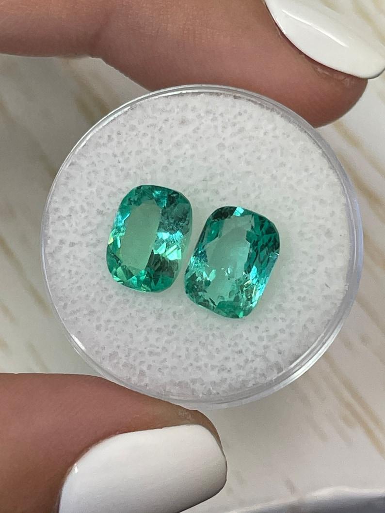 A. Stone: Smeraldo
Peso totale: 4,59-tcw
Forma: Taglio a cuscino
Chiarezza: Trasparente
Lucentezza: Eccellente-Molto buona
Colore: Verde chiaro e bluastro
Misure: 9.46mm x 7.09mm x 4.60mm // 9.44mm x 7.09mm x 5.02mm
Origine geografica: