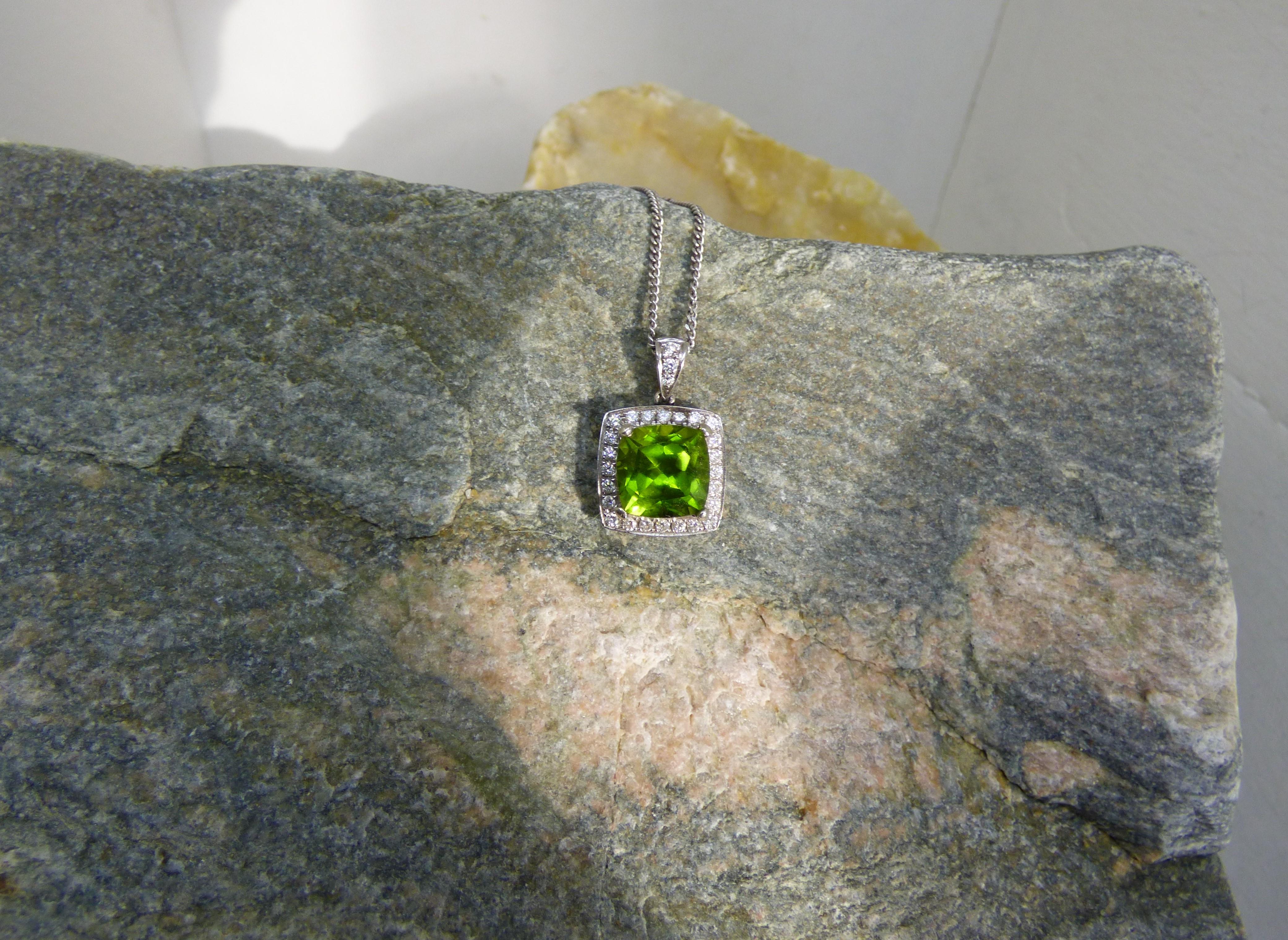 The 10X10mm cushion cut Peridot in this pendant is bright and colourful.  The 4.5ct stone is surrounded by 27 Diamond with a total Diamond weight of .32ct. The pendant is handmade in 14K white gold and hallmarked by the Dublin Assay Office.  The
