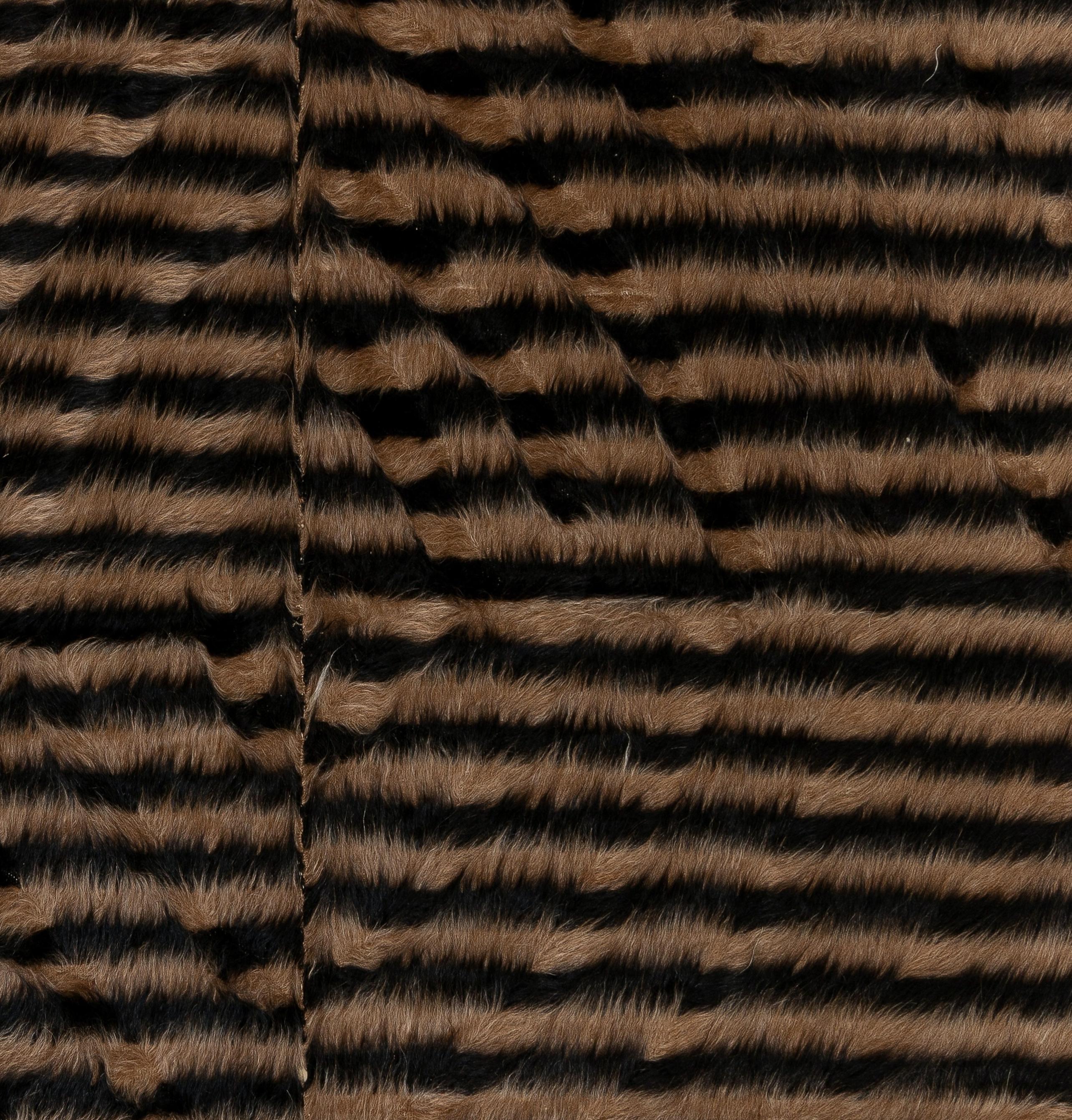 A new hand-woven rug from Eastern Turkey.
The rug is made of an inch long, soft mohair pile on cotton foundation, featuring a striped design in natural, un-dyed colors of black and light brown. 
It is very soft, like a Navajo blanket, it can be