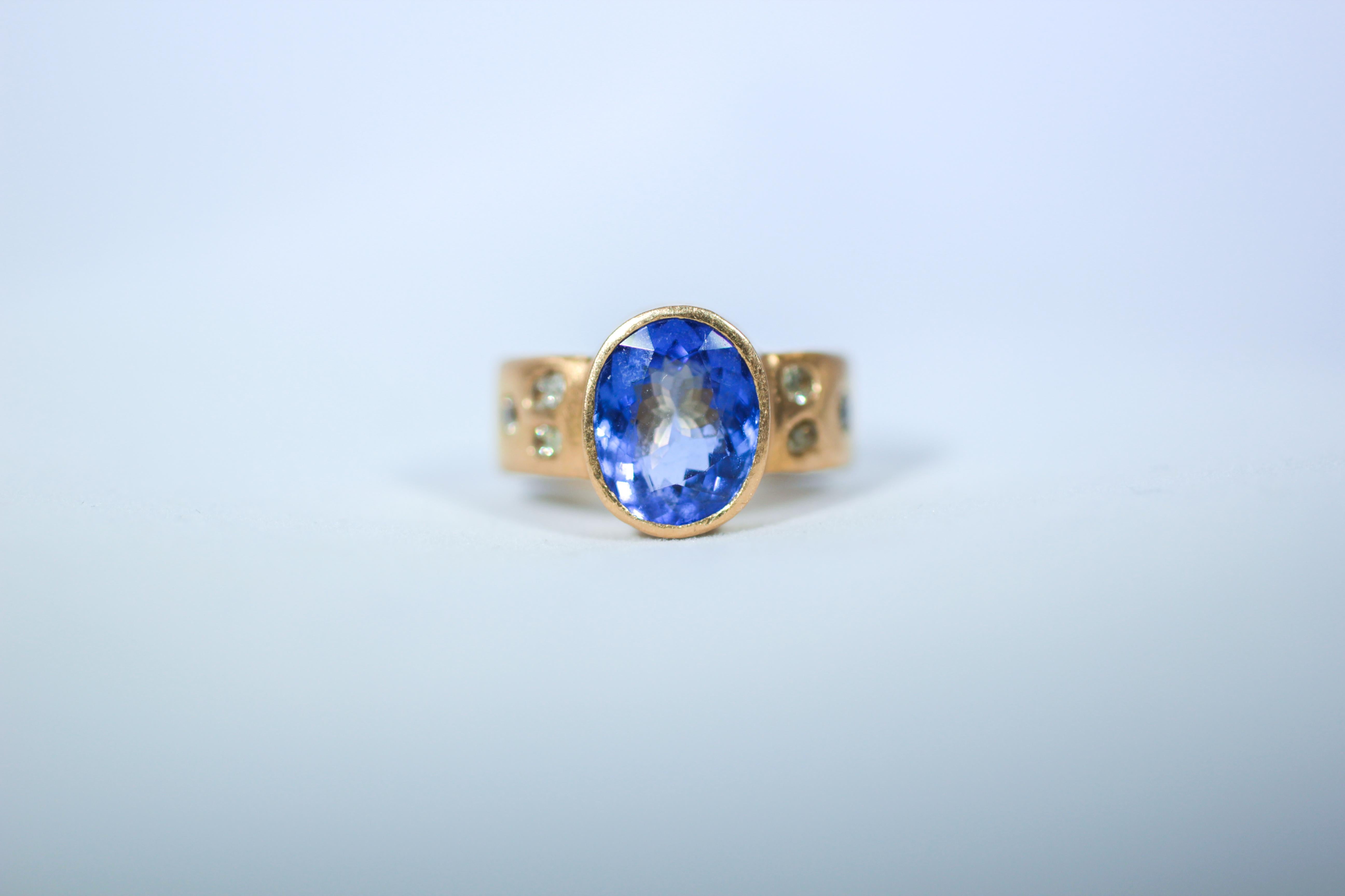 Bridal 21K gold ring featuring 4.6Ct Tanzanite solitaire surrounded by a melee of six yellow free-form rose-cut diamonds. Our elegant Violet Ring delivers a pop of color. The intense blue-purple tanzanite is set in a lush-colored satin 22K gold