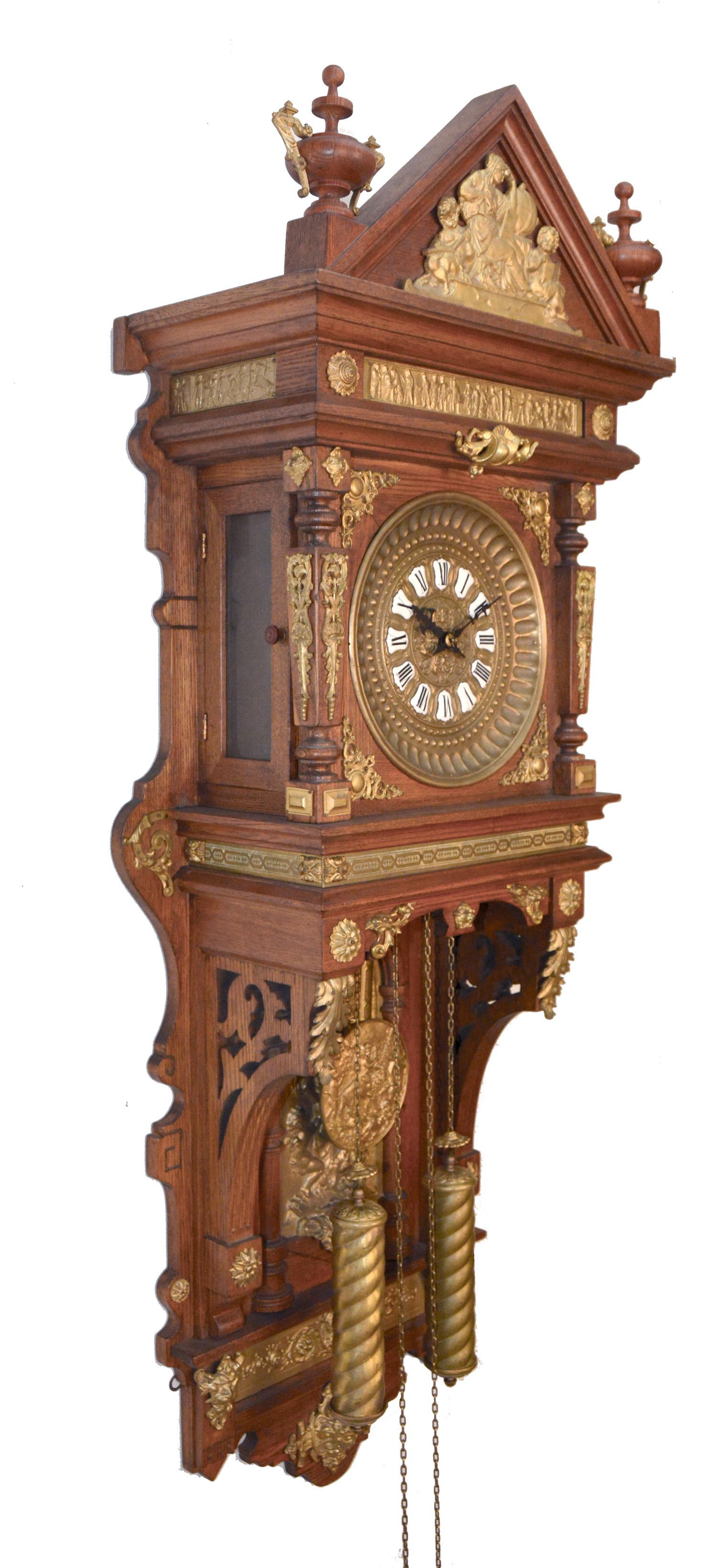 Here is an 'Antique Hanging' model double weight wall clock. The entire clock case and the finials are made of solid oak. The all solid brass casting decoration on the whole clock body is just breath taking. The time shows on 12 individual porcelain