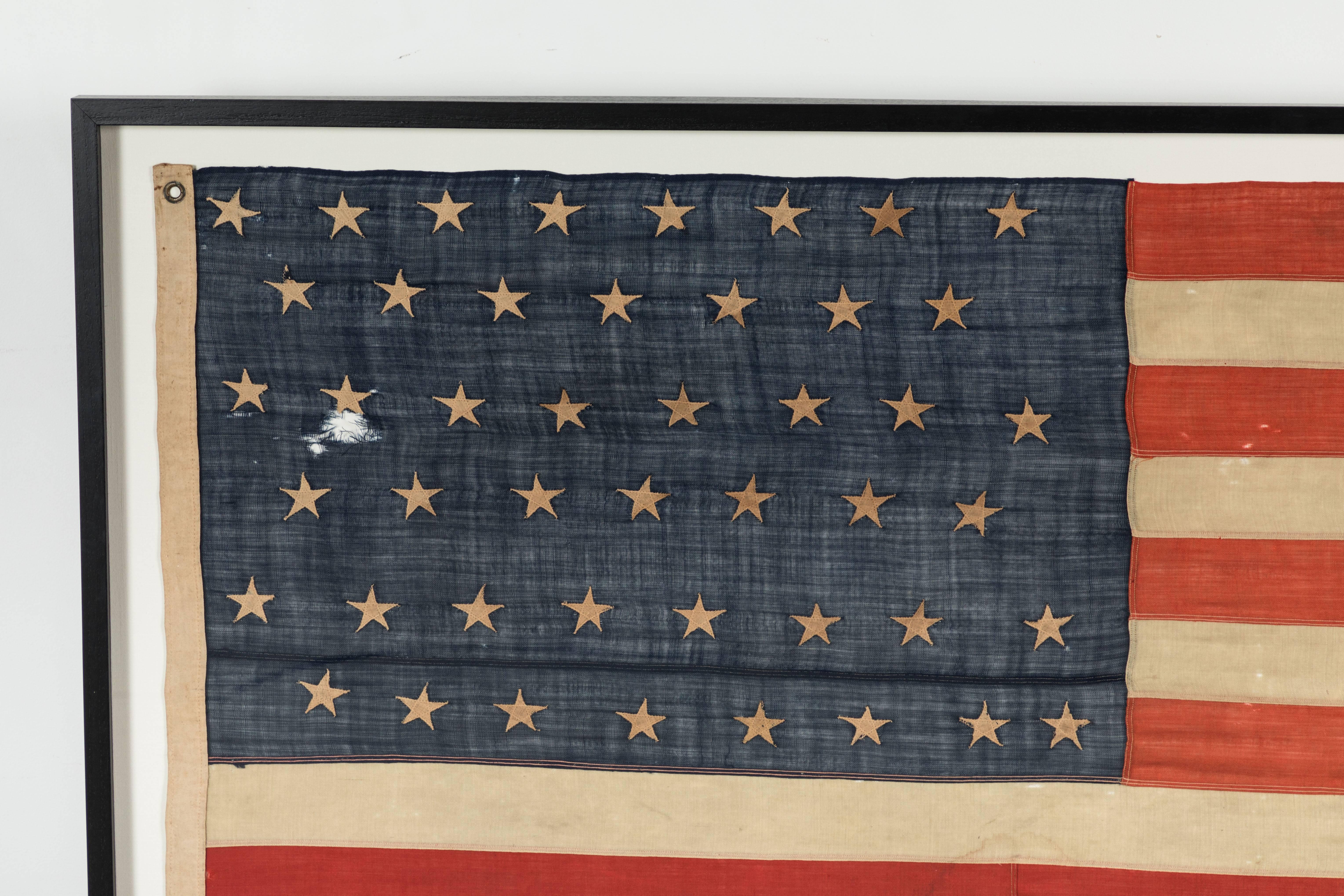 Nice large scale framed American 46 star flag. Hand-stitched and randomly applied folk art stars. The rest of the flag construction is machine stitched. Exact measurements are 86.5 wide by 46