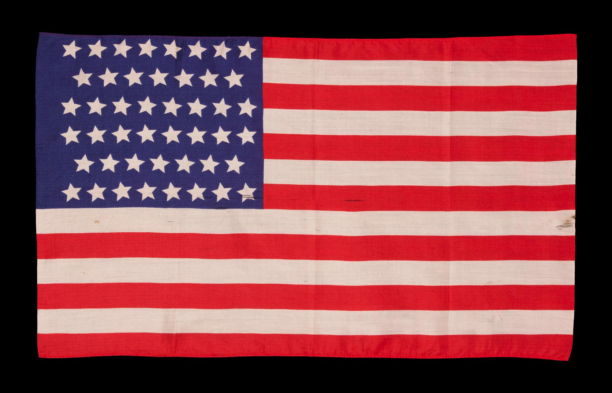 46 STAR, SLIK, ANTIQUE AMERICAN FLAG, WITH STARS IN CANTED ROWS, REFLECTS THE ADDITION OF OKLAHOMA TO THE UNION DURING THE PRESIDENCY OF THEODORE ROOSEVELT, 1907-1912

46 star American national parade flag, printed on silk, bound at the top and