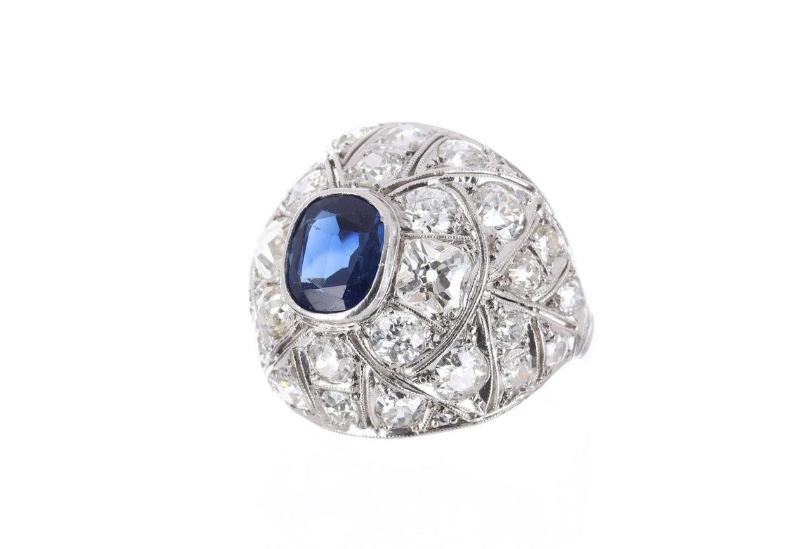 Featured here is a very special vintage ring from the early 1920's with sapphire and old European cut diamonds! This Art Deco piece is quite impressive and it is sure to get her noticed. The center sapphire is a cushion cut stone filled of life and