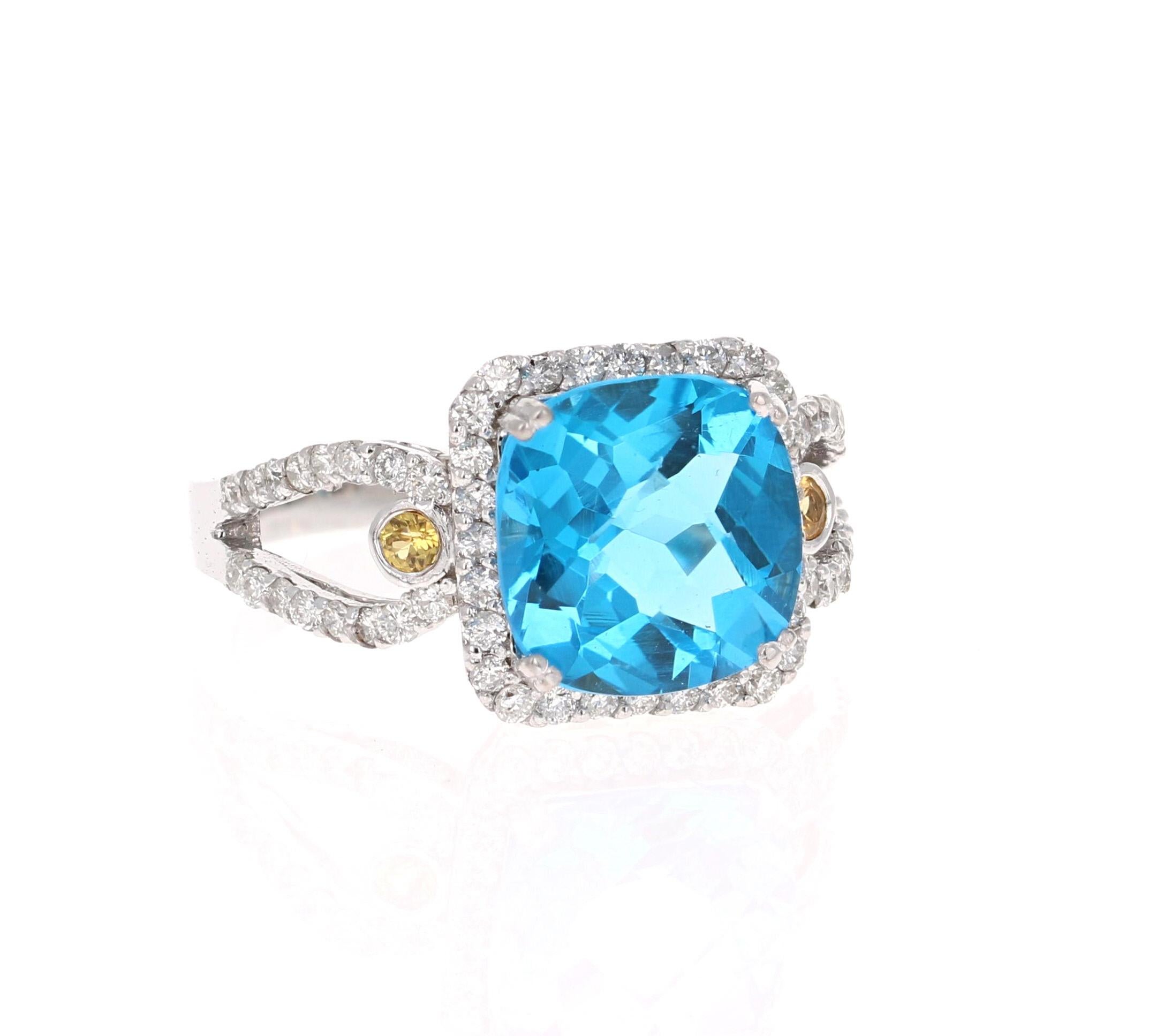 This beautiful Cushion Cut Blue Topaz and Diamond ring has a stunningly vibrant Blue Topaz that weighs 3.97 Carats. It is surrounded by a Halo of 60 Round Cut Diamonds that weigh 0.55 Carats and has 2 Yellow Sapphire accents on the shank that weigh