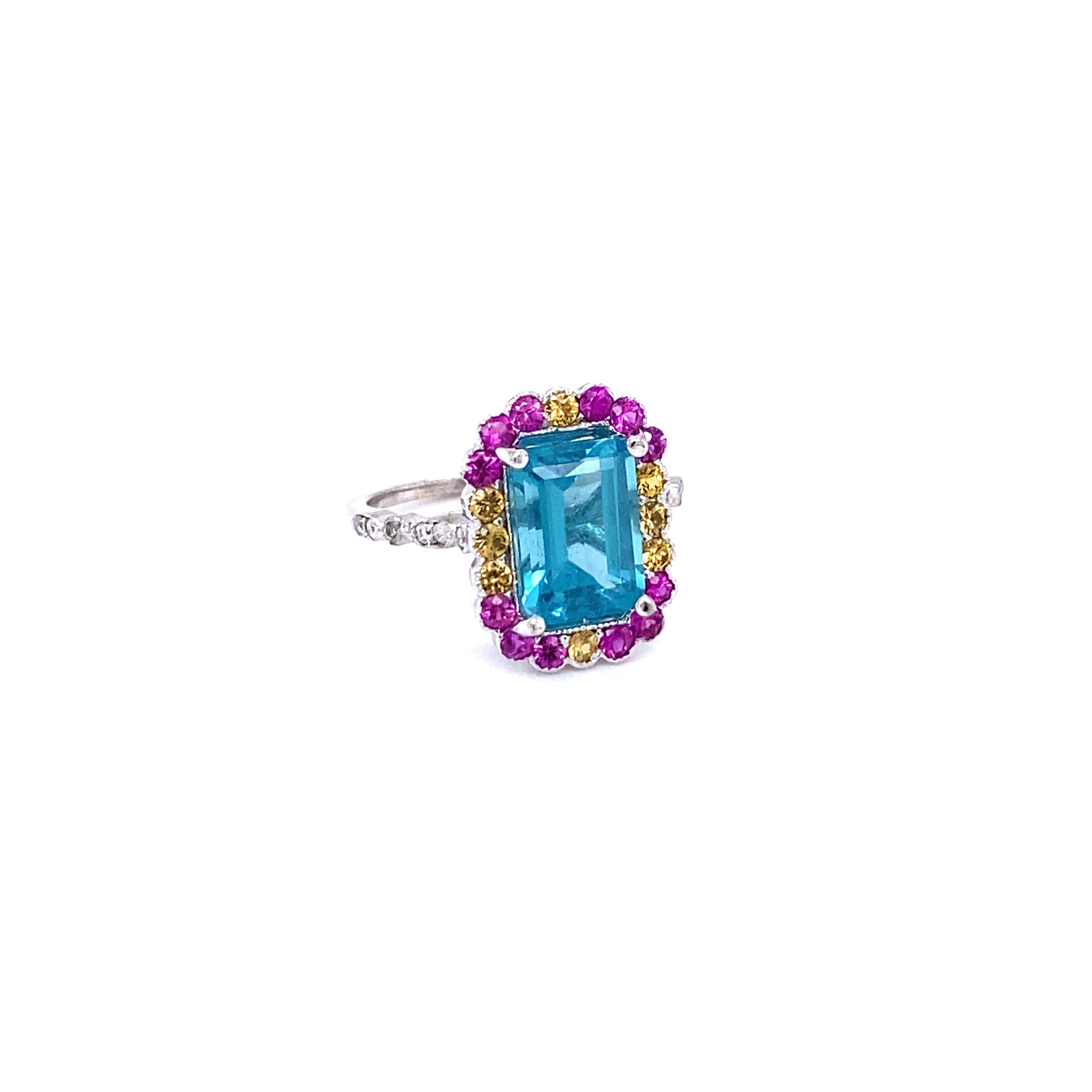 This ring has a 3.62 Carat Emerald Cut Apatite in the center of the ring and is surrounded by 20 Pink and Yellow Sapphires that weigh 0.88 Carats and 12 Round Cut Diamonds that weigh 0.12 Carats (Clarity: SI, Color: F).  The total carat weight of