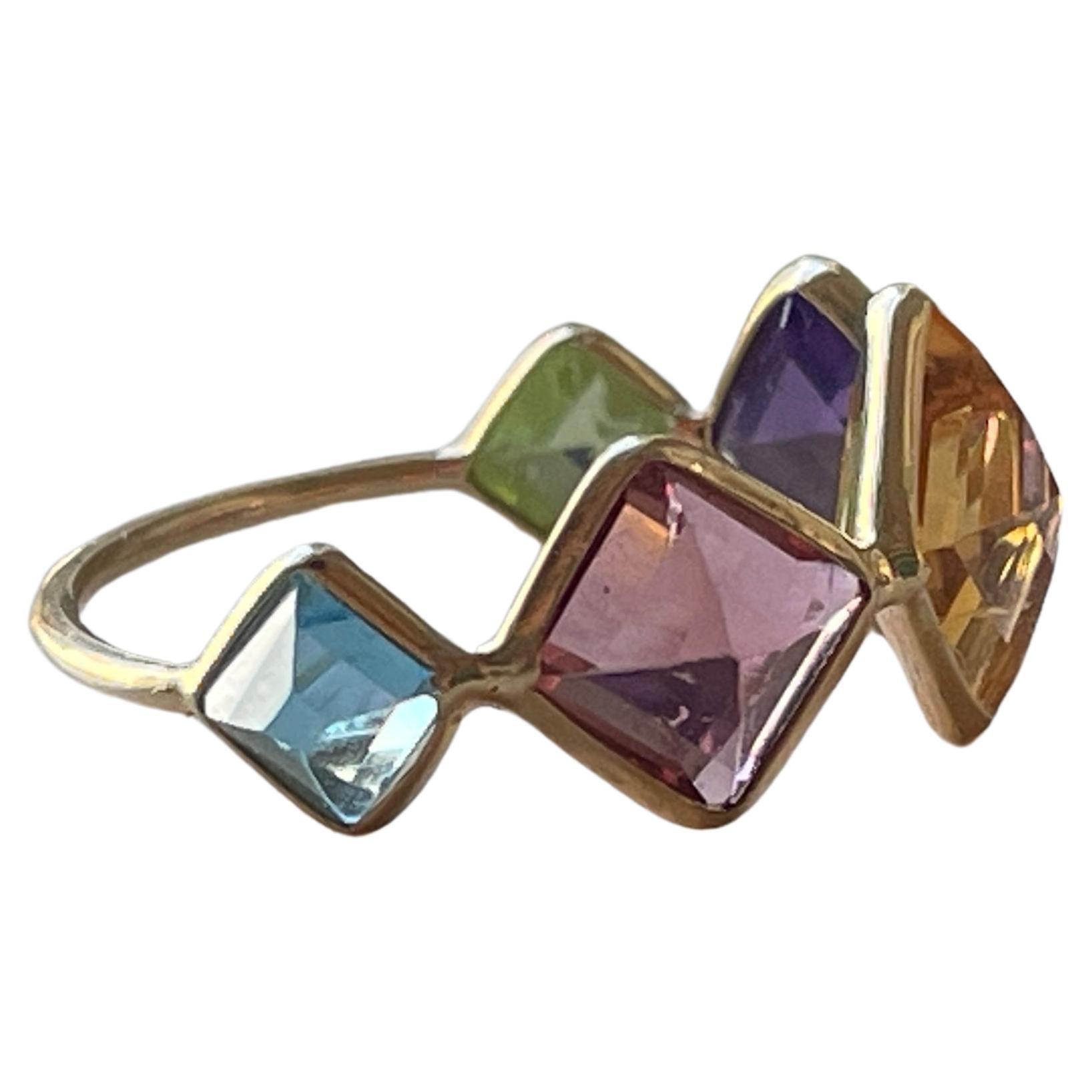 The beautiful ring is comprised of 5 Emerald Cut gemstones including, Aquamarine, Pink Tourmaline, Yellow Tourmaline, Amethyst, & Peridot. The Gemstones are set upside down in 18k gold bezel allowing for the point of the stone to be on the top of