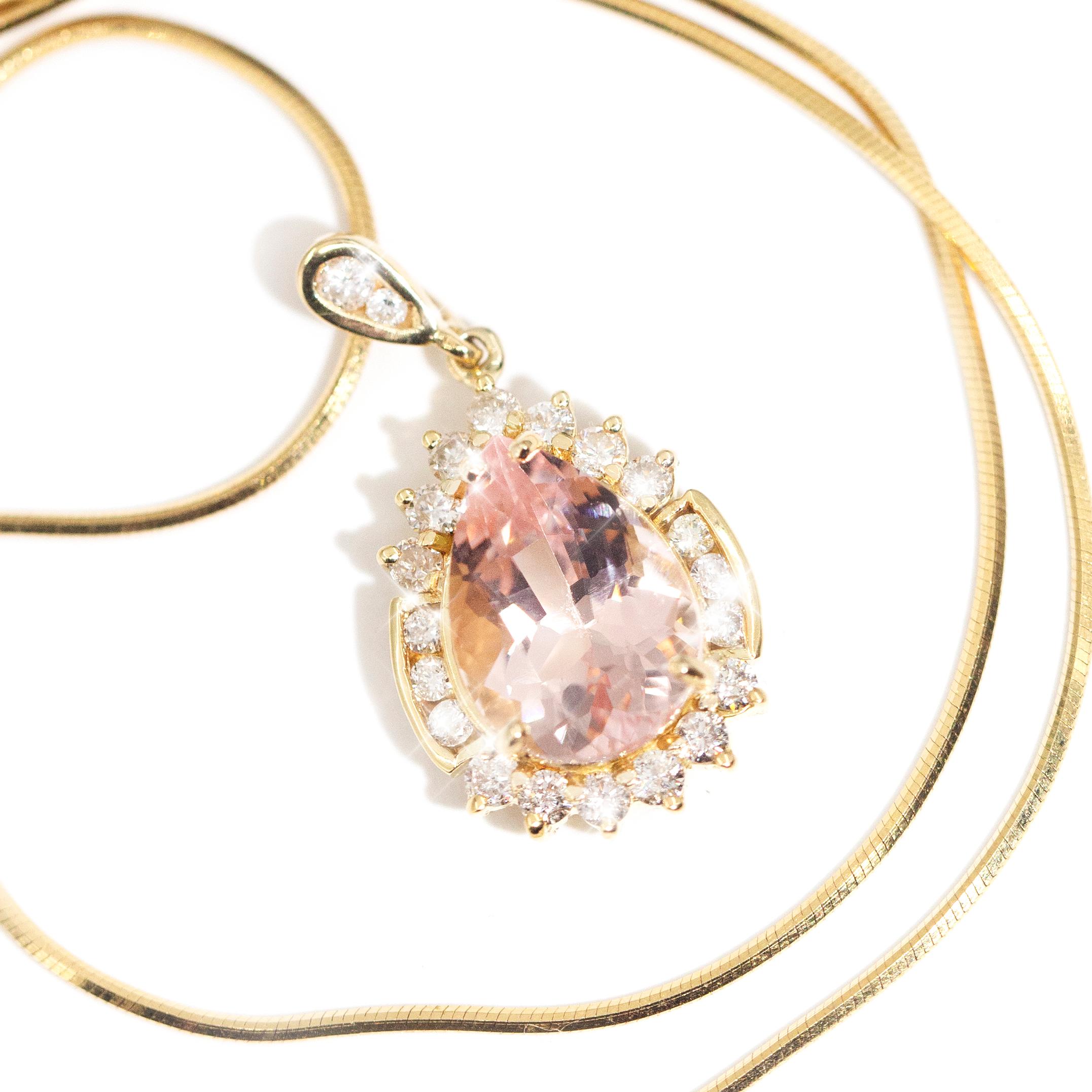 Forged in 18 carat yellow gold, this gorgeous vintage pendant features an enchanting 4.65 carat light pink drop shape morganite encompassed by shining round brilliant diamonds. Further, the bail is embellished with two sparkling round brilliant cut