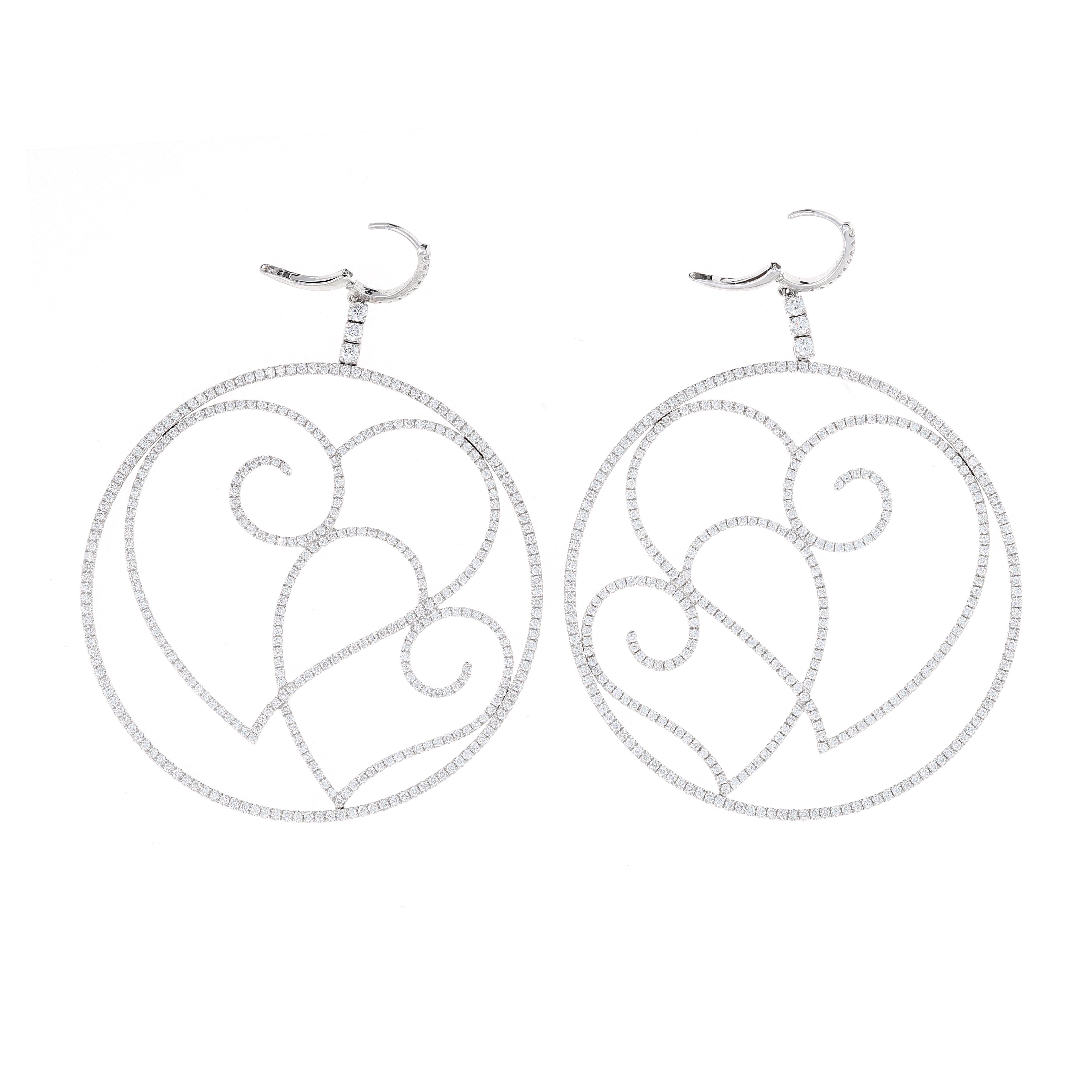 These large diamond hoop earrings are the perfect Mother's Day gift. The earrings are made in 18 karat white gold   and dangle from a diamond hoop. The design showcases 2 side by side intertwined heart shapes. 
There are a total of 4.69 carats in