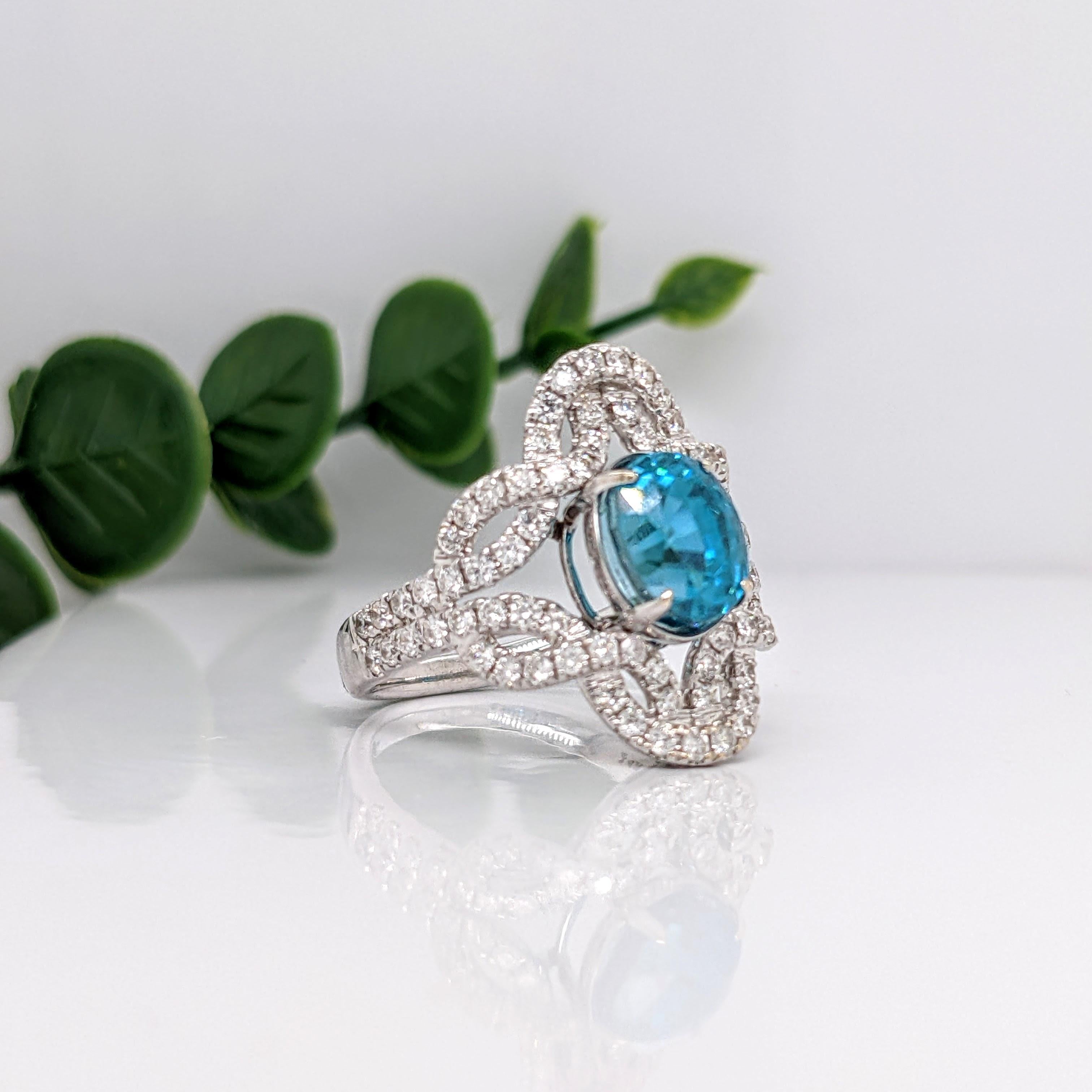 This embellished ring features a stunning vibrant 4.6ct oval blue zircon in a 14K white gold prong setting with pave diamond accents on a unique woven shank design. This ring makes for a stunning accessory to any look!  A fancy ring design perfect