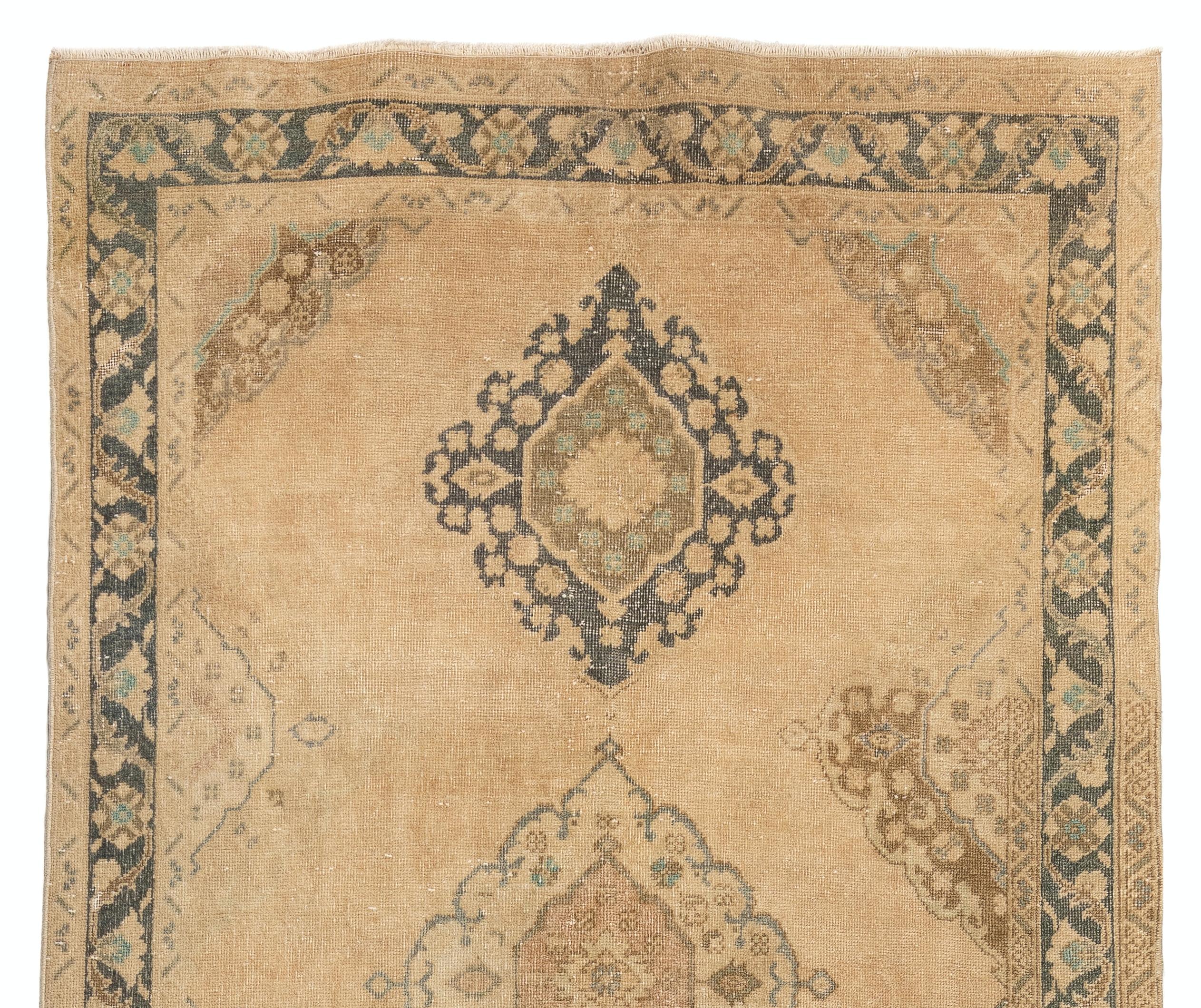 A vintage Turkish runner rug in soft, warm golden sand color with touches of moss green, teal, brownish pink and charcoal gray, featuring a well-drawn multiple linked medallions design. 

The rug was hand-knotted in the 1960s and has low wool on