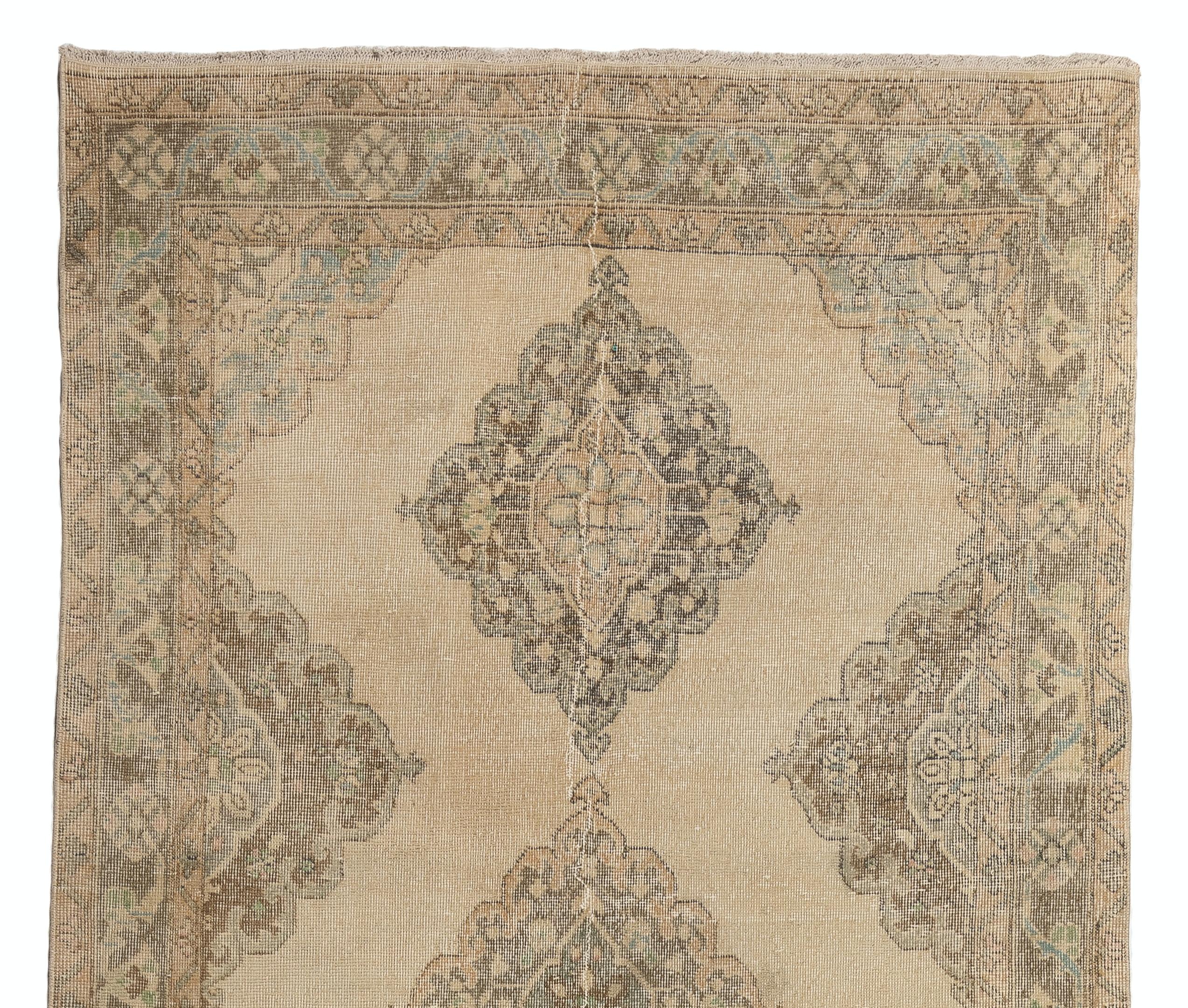 A vintage Turkish runner rug featuring a design of multiple linked curvilinear medallions against a sand beige background in brown, fawn and aqua green colors. 
The rug was hand-knotted in the 1960s and has low wool pile on cotton foundation. It is