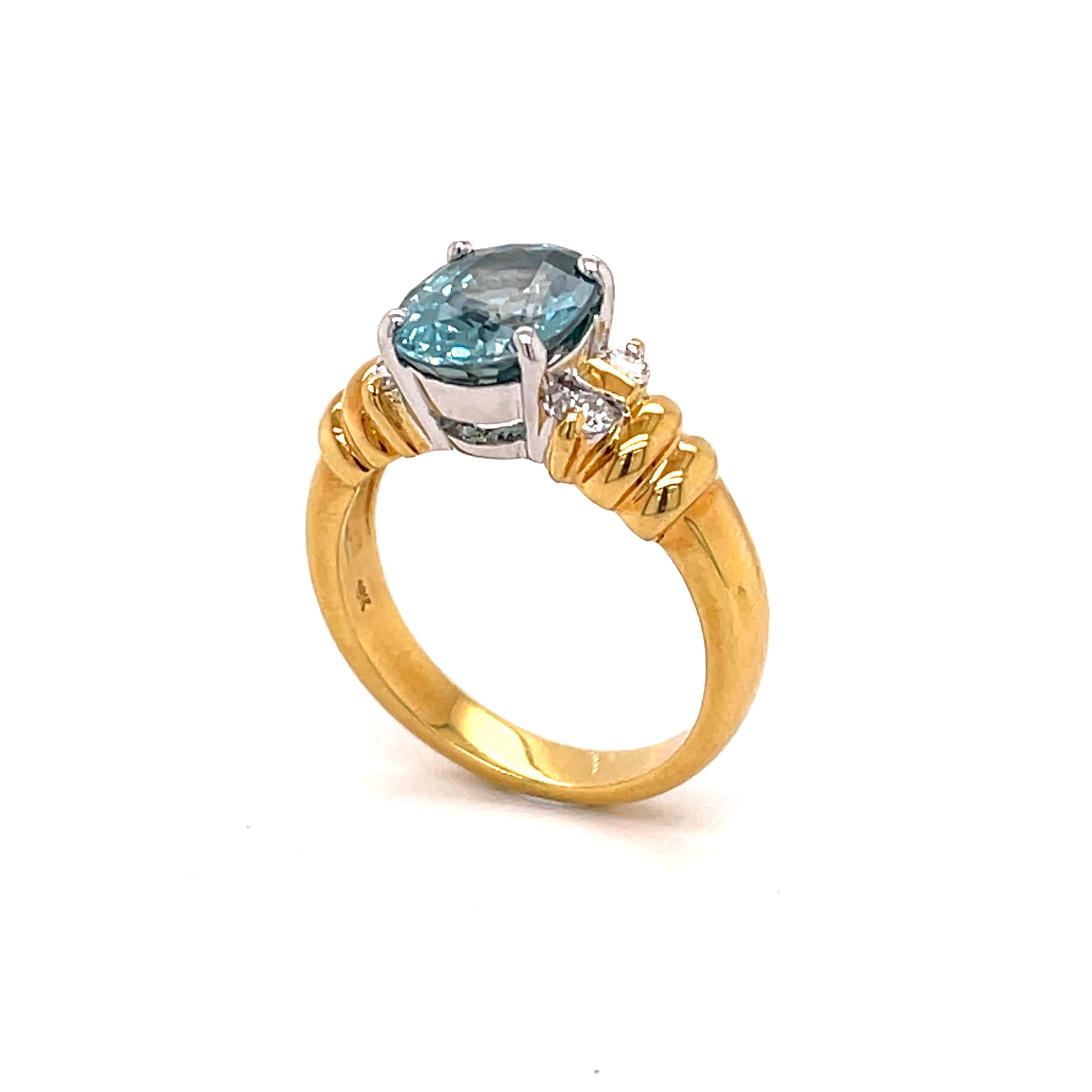 This December birthstone ring of blue Zircon has a Cambodian cut oval stone that is 10 x 8 mm and weighs 4.70 carats. We usually re-cut all of our blue Zircons stones, but this particular one faced up well. 
It has 2 Diamonds on each side (total 4)